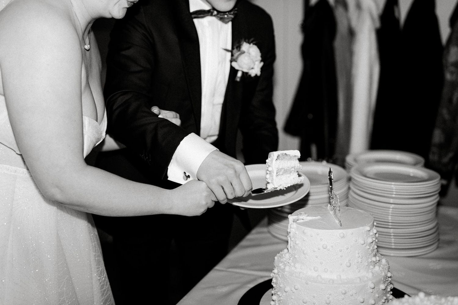 Black and white wedding reception photos showing guests enjoying cake and desserts at an elegant venue.