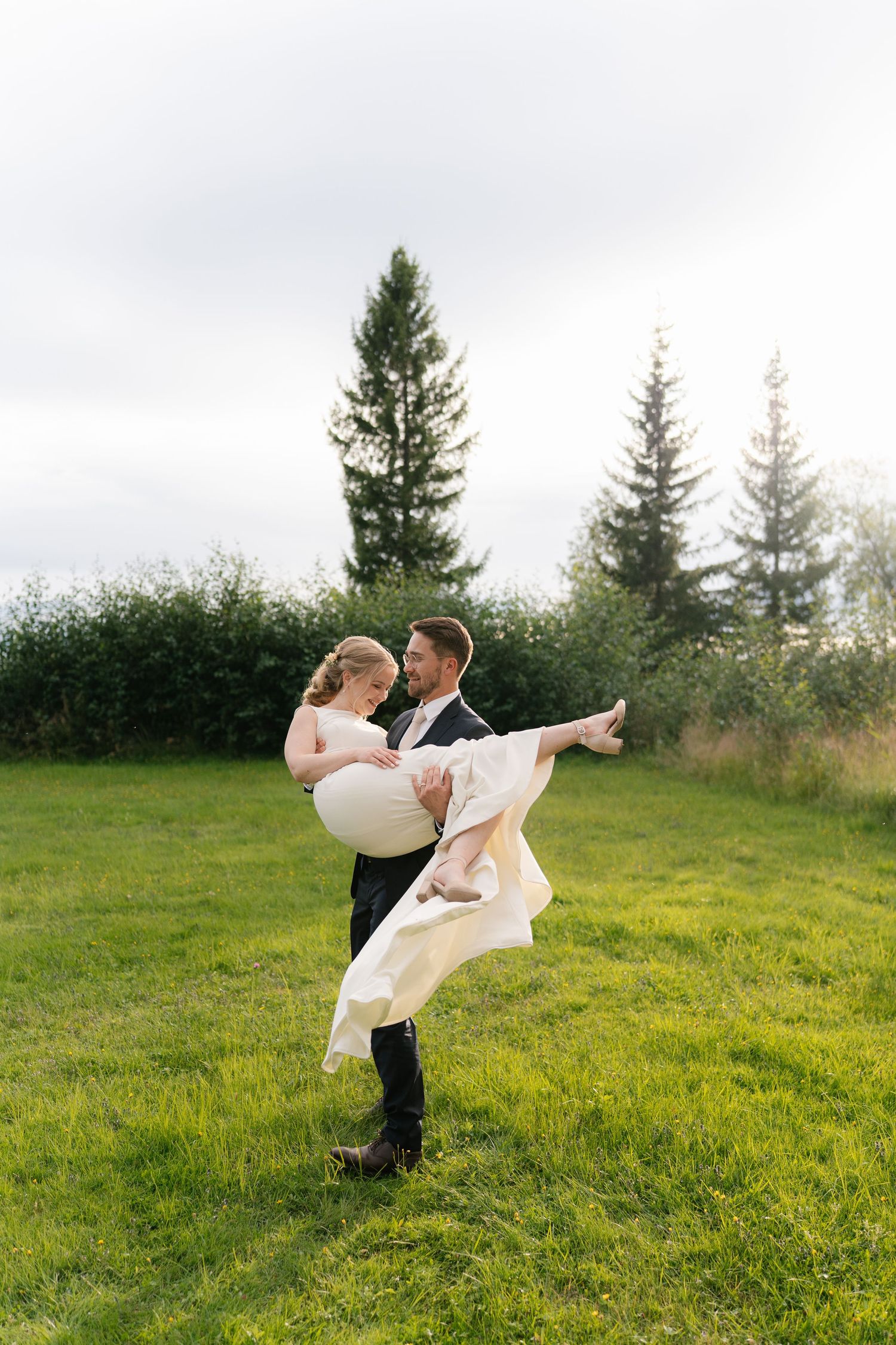 A romantic wedding photoshoot sequence showing a couple spinning and embracing in a sunlit meadow with evergreen trees.
