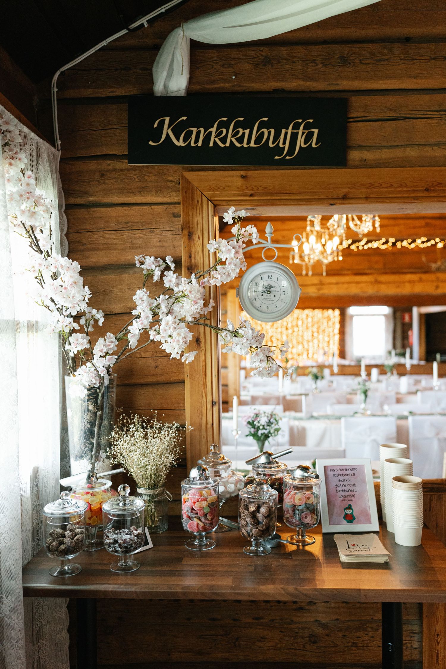 Rustic wedding candy bar with glass jars and decorative elements under a Karkkibuffi sign.