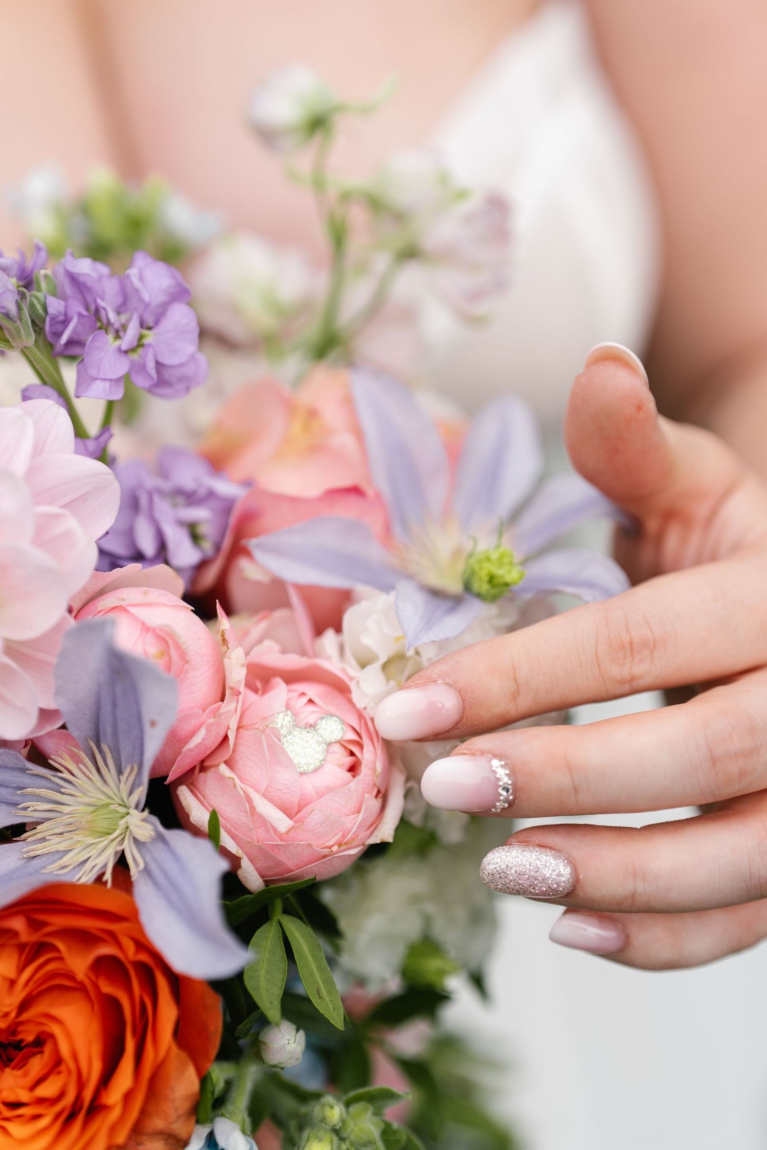 Delicate close-up details of pink and purple wedding flowers with manicured hands.