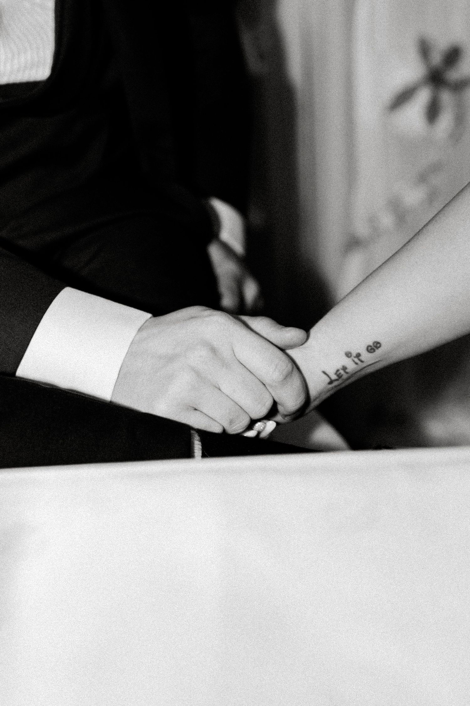 Black and white close-up of hands during a wedding ceremony moment.