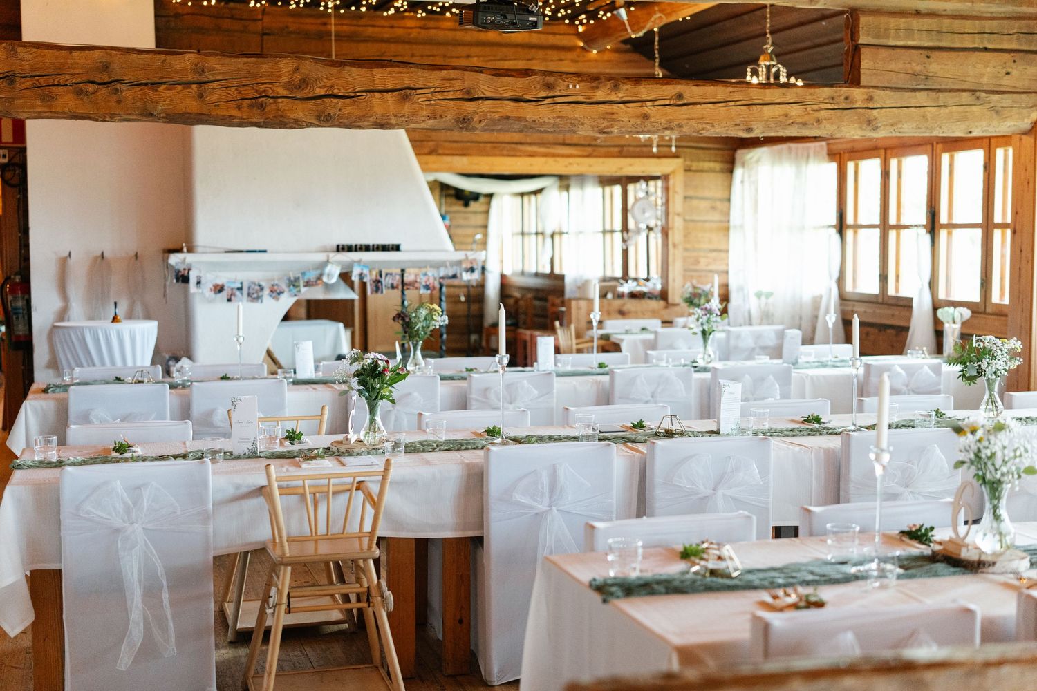 Bright rustic wedding venue with wooden walls and white table settings.