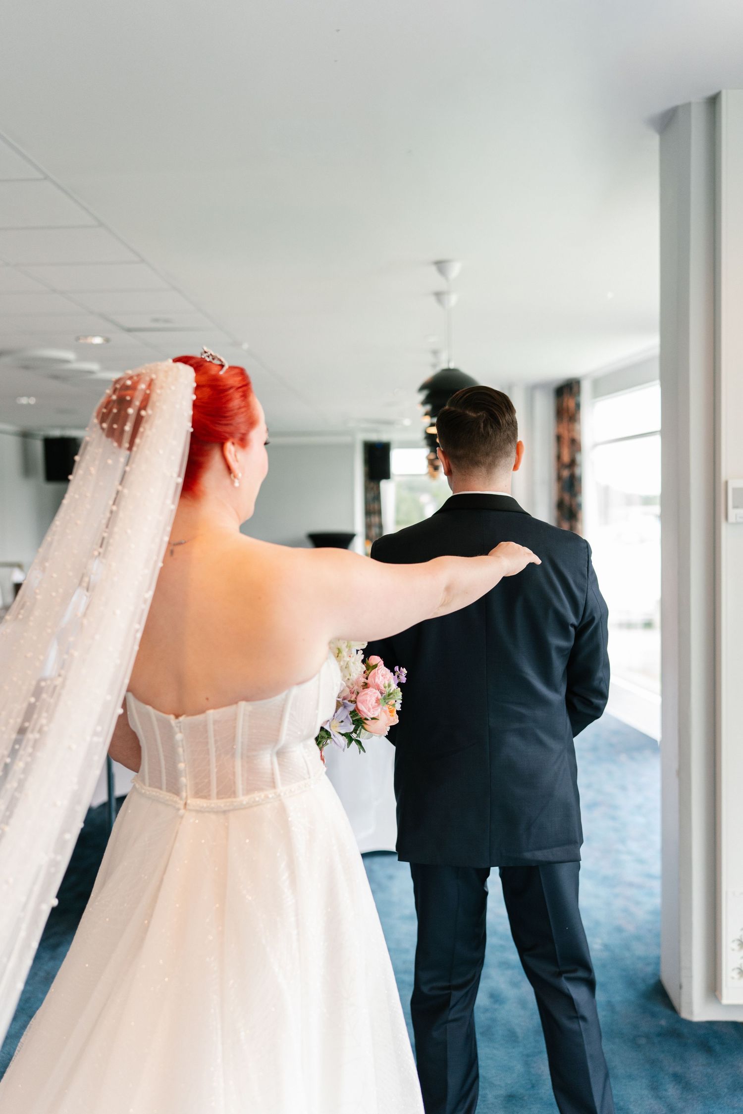 Wedding first look sequence showing couple in white dress and dark suit in bright hallway.