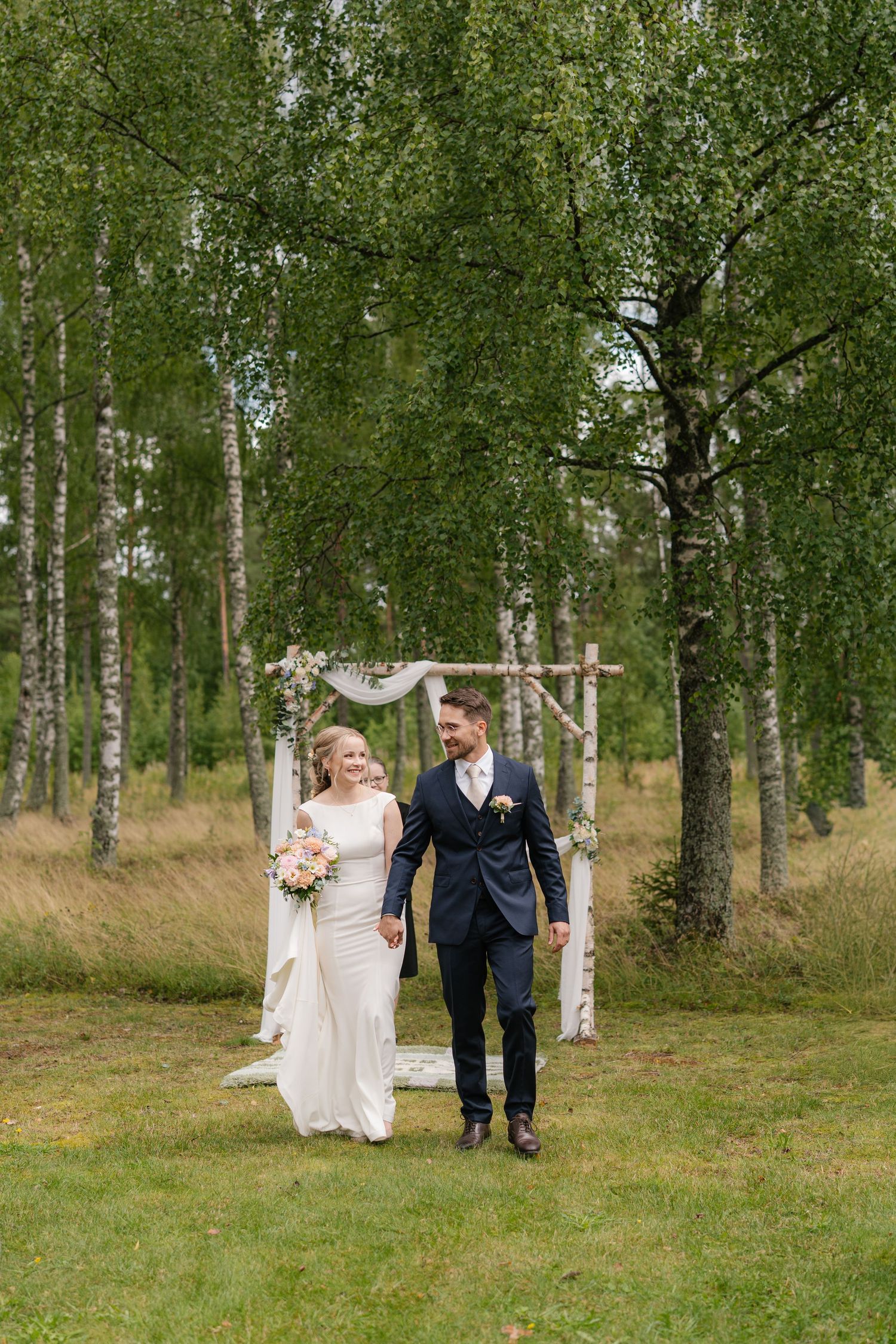 Newlyweds celebrate their marriage in a scenic woodland setting with birch trees and natural decor.