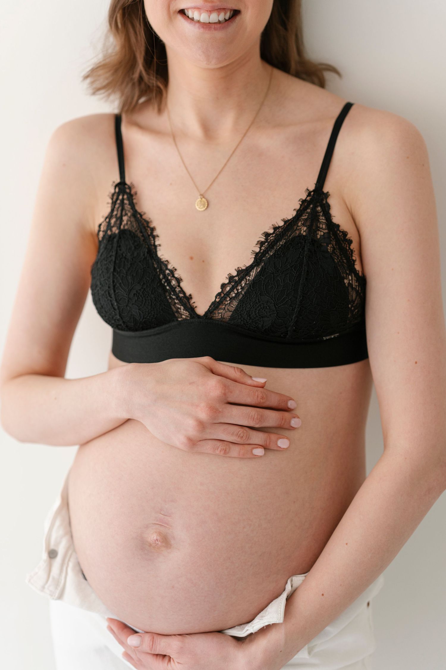 Intimate maternity portraits featuring black lace bralette and natural expressions.