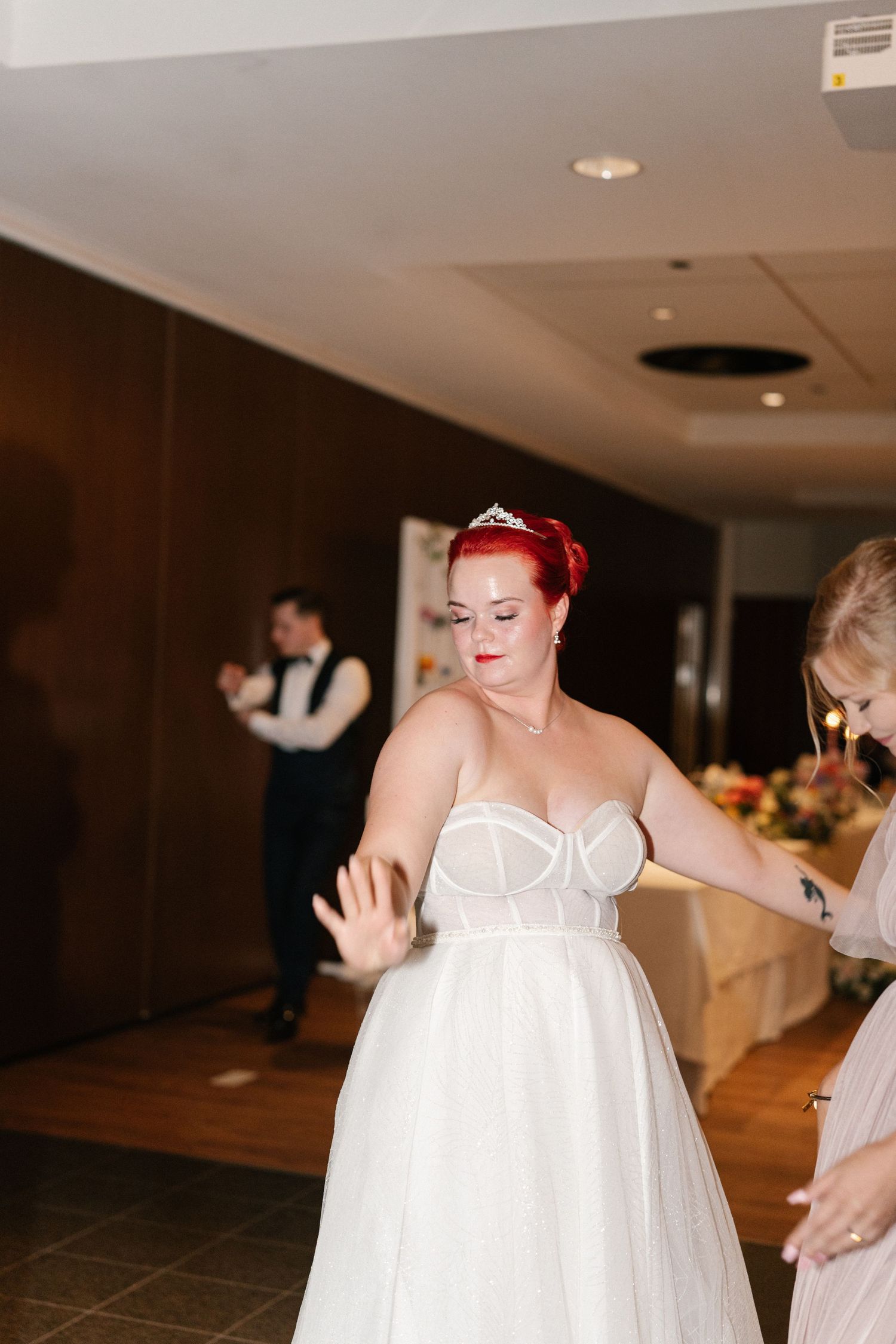 A bride in a white gown dances joyfully at her wedding reception.