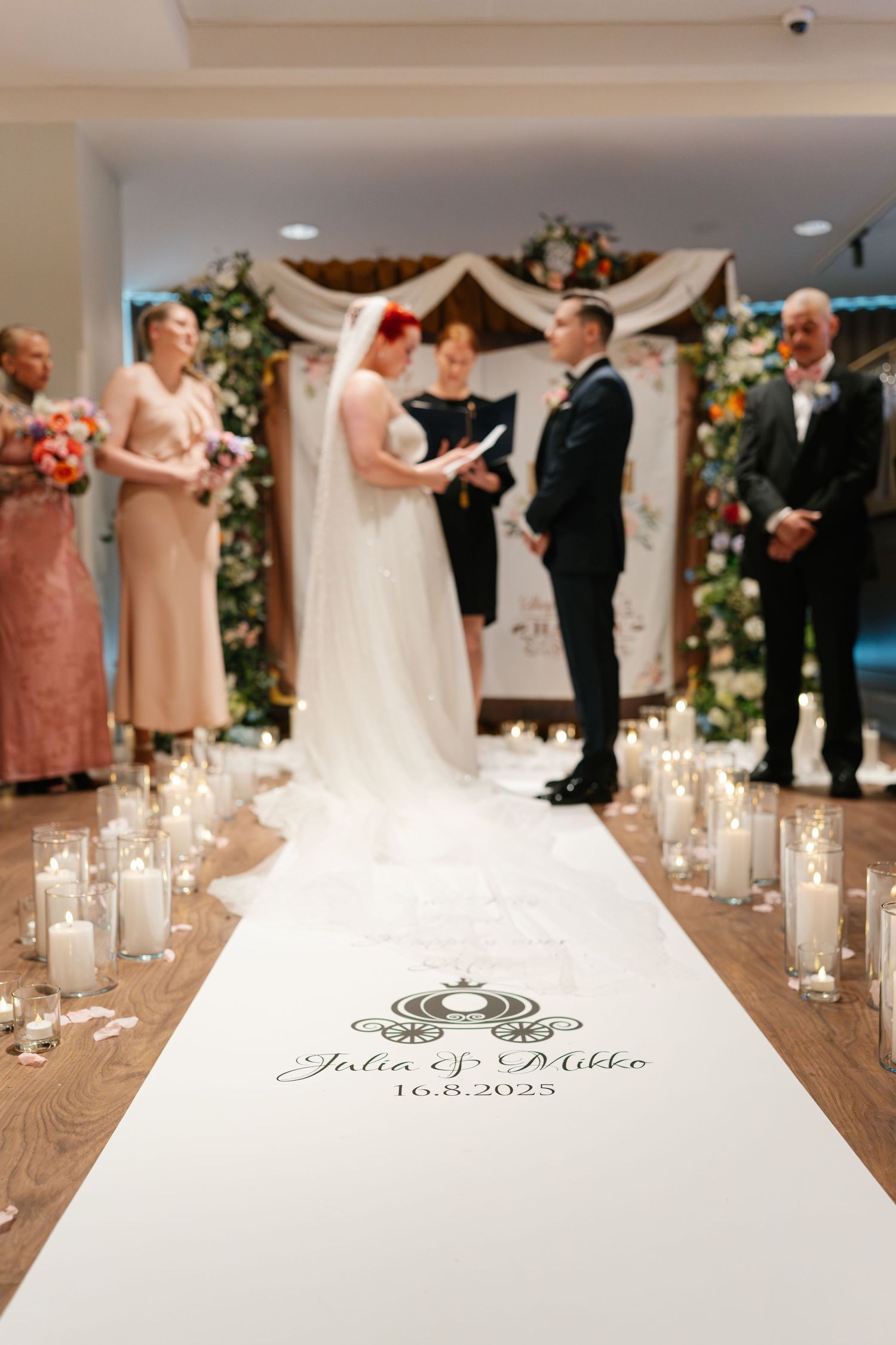 Wedding aisle runner with monogram design surrounded by lit candles during ceremony.