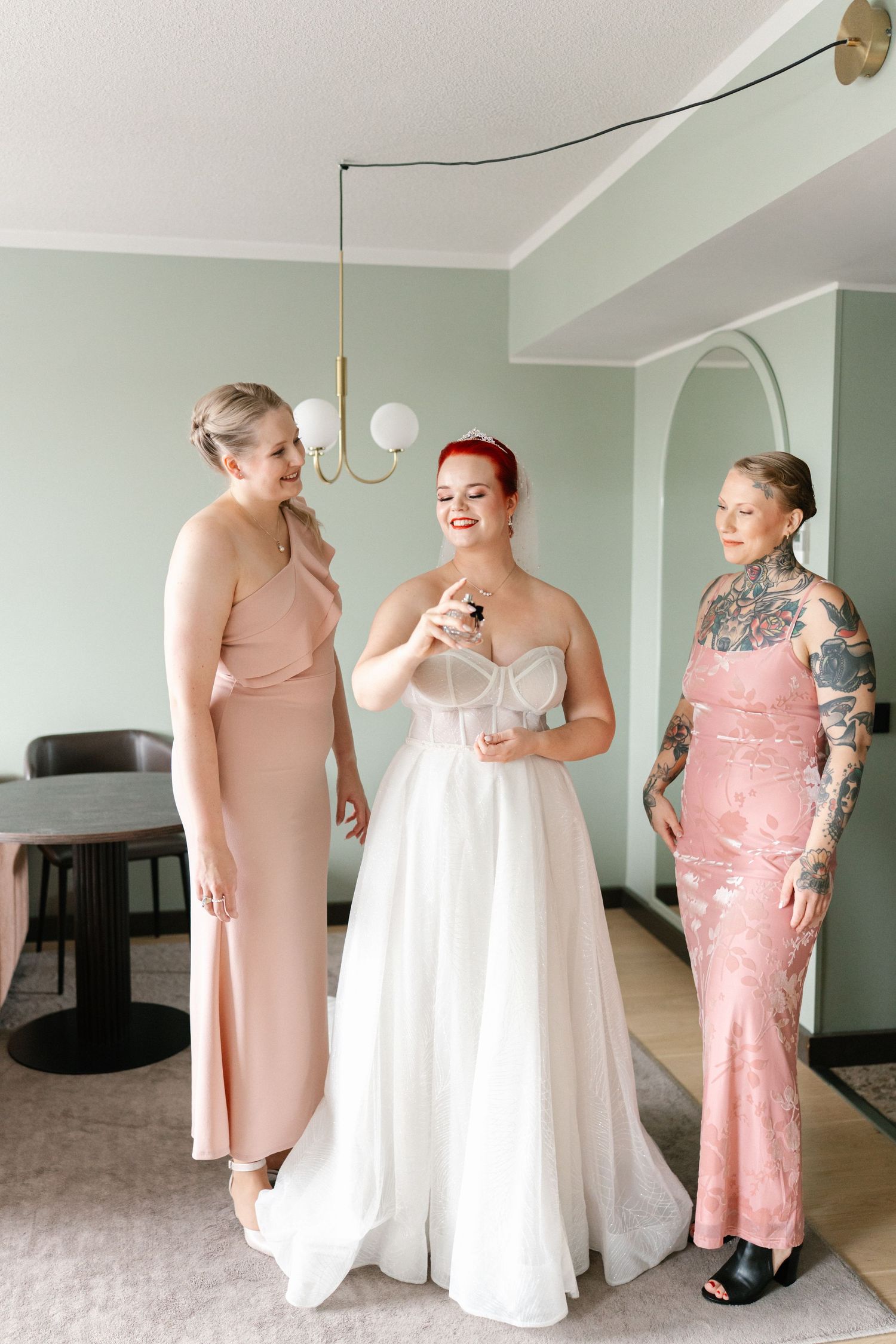 Wedding party members in pink dresses share joyful moments while getting ready.