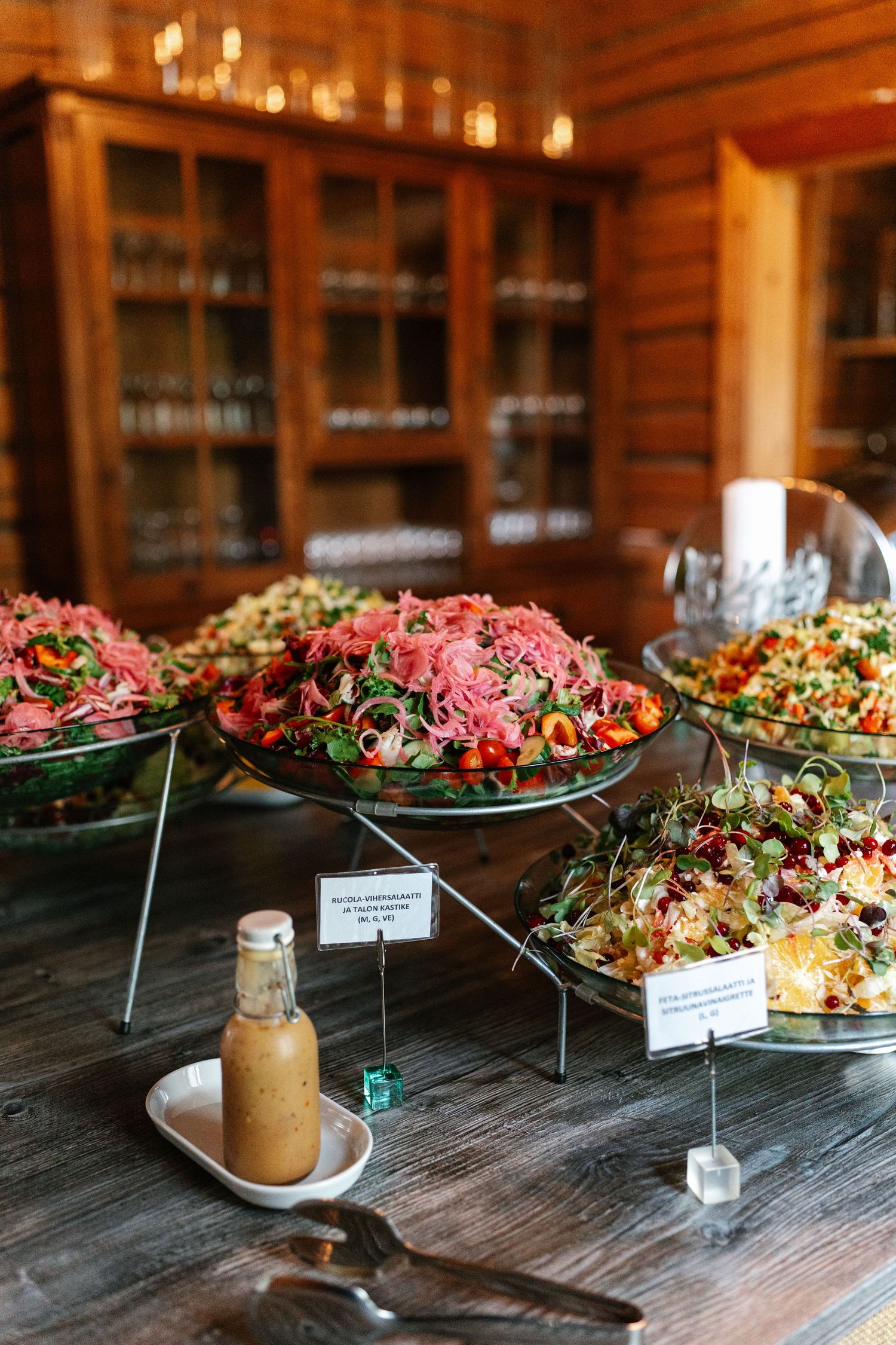 Beautifully presented buffet spread with colorful salads and dressings on a rustic wooden table.