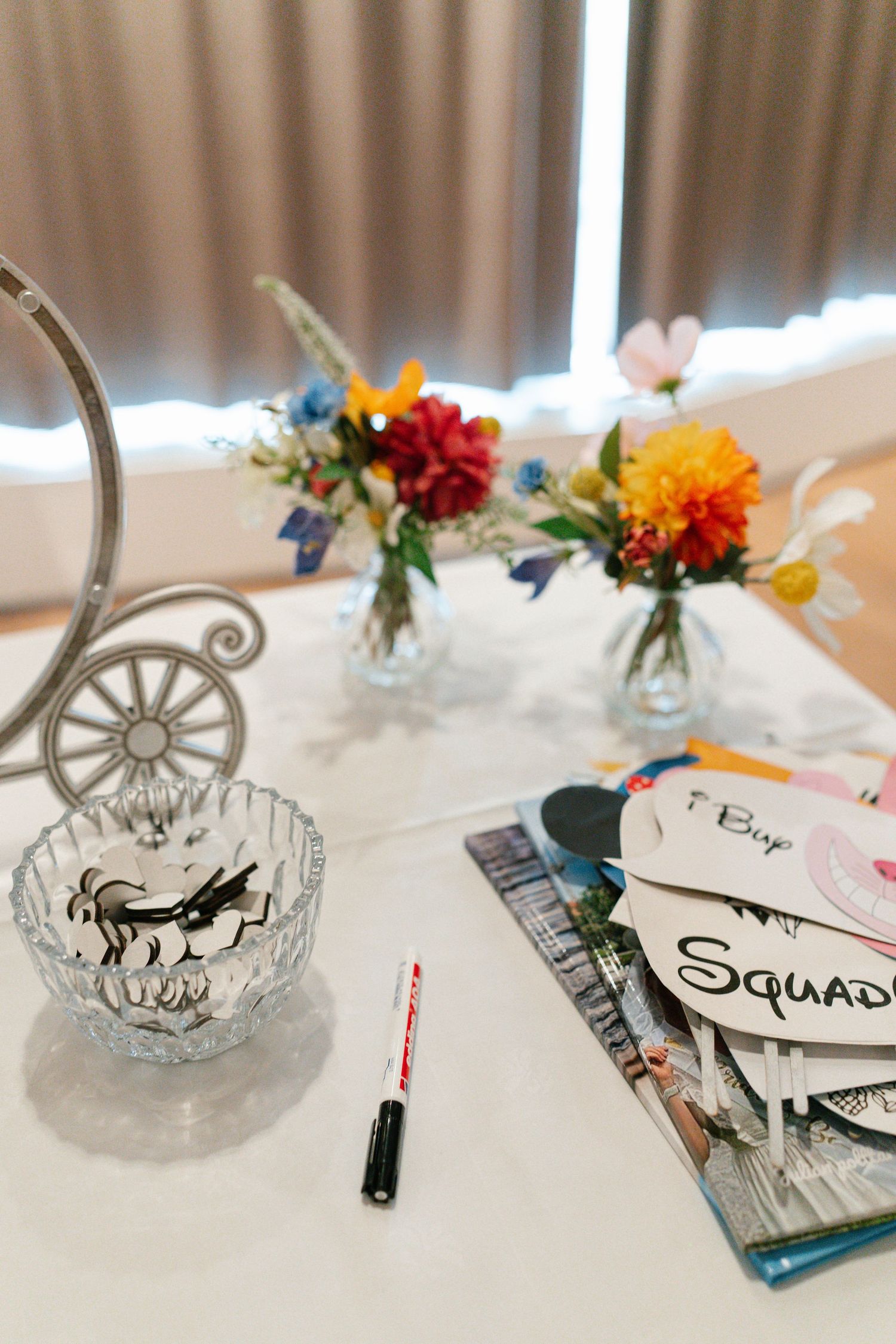 Wedding table settings with artistic drawings and small colorful flower arrangements in glass vases.