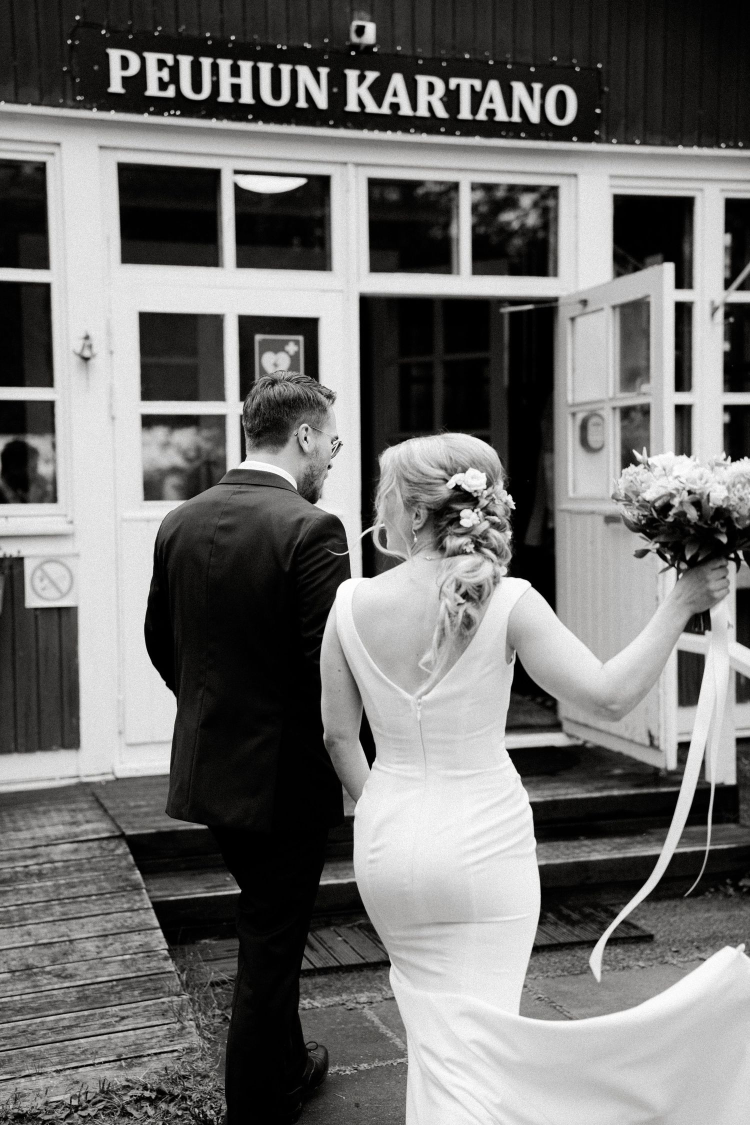 Black and white wedding photos outside Peohun Kartano building with elegant couple.