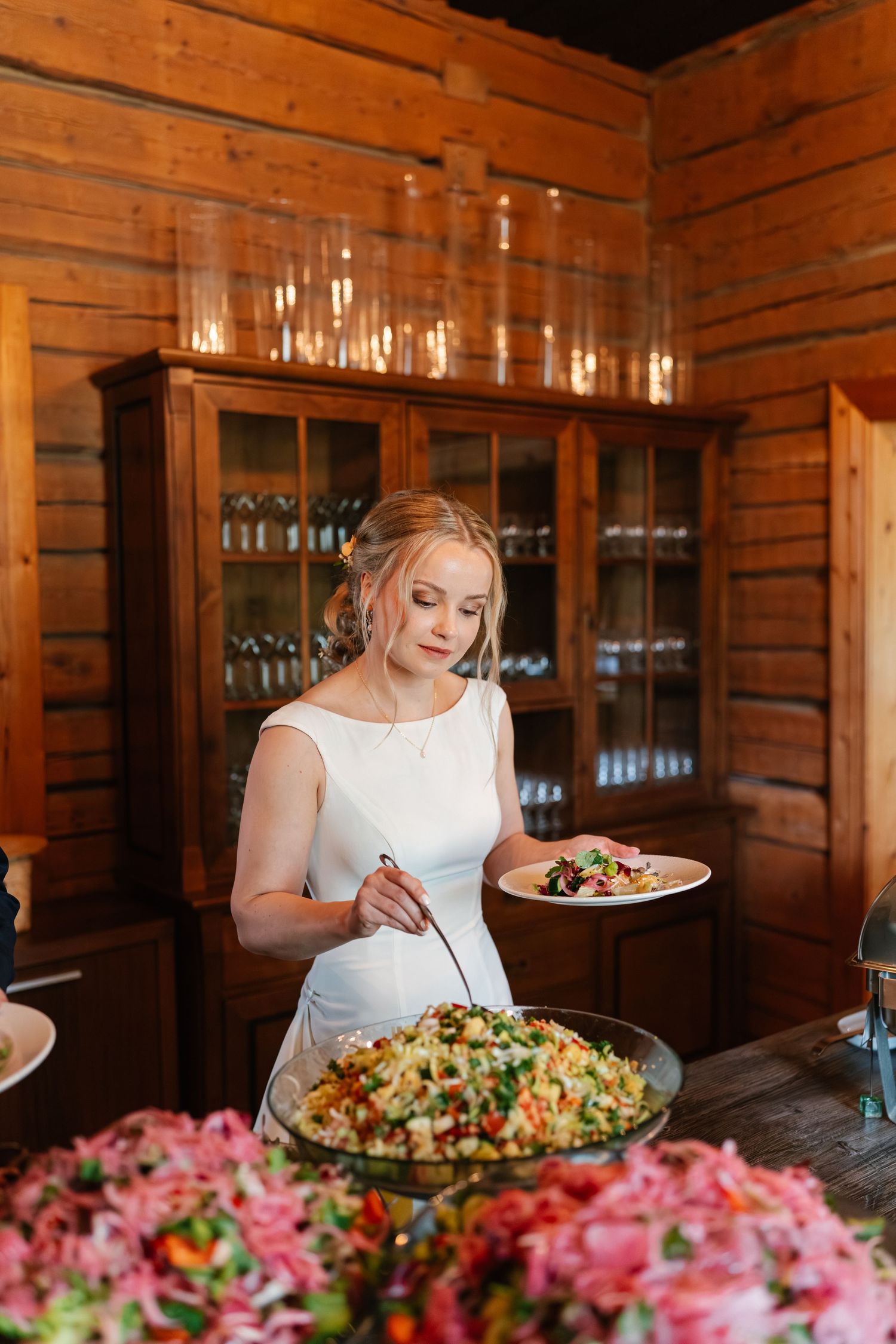 Rustic wooden dining room with fresh salads and pink floral arrangements on display.