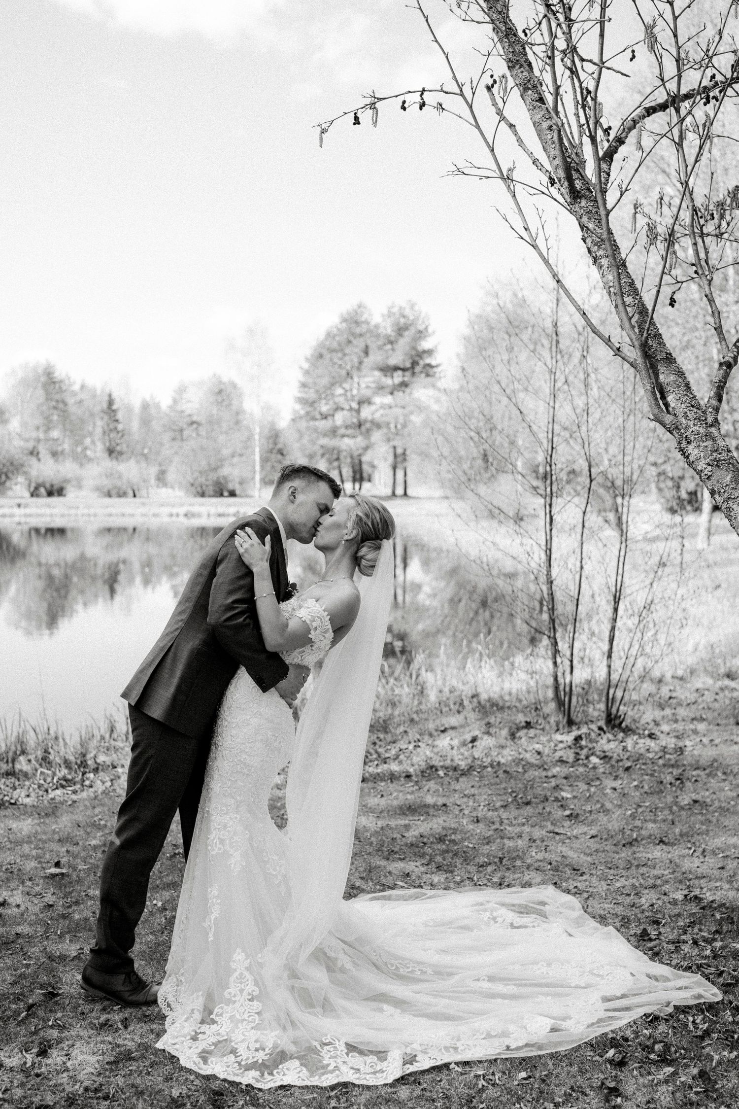 Black and white wedding portraits showing couple's romantic moments by a lakeside setting.