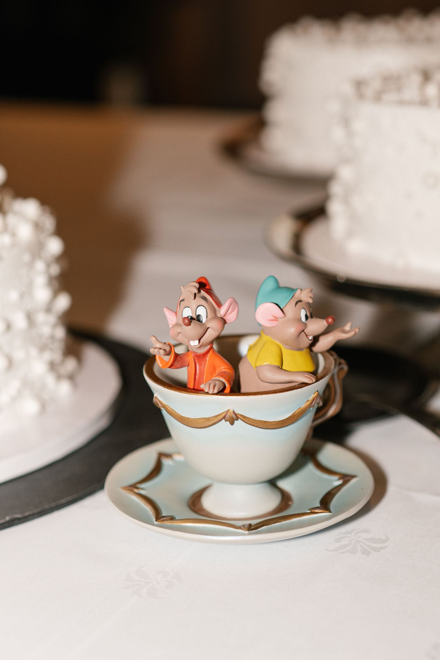 Decorative tea cups with miniature figures arranged on plates at wedding reception.