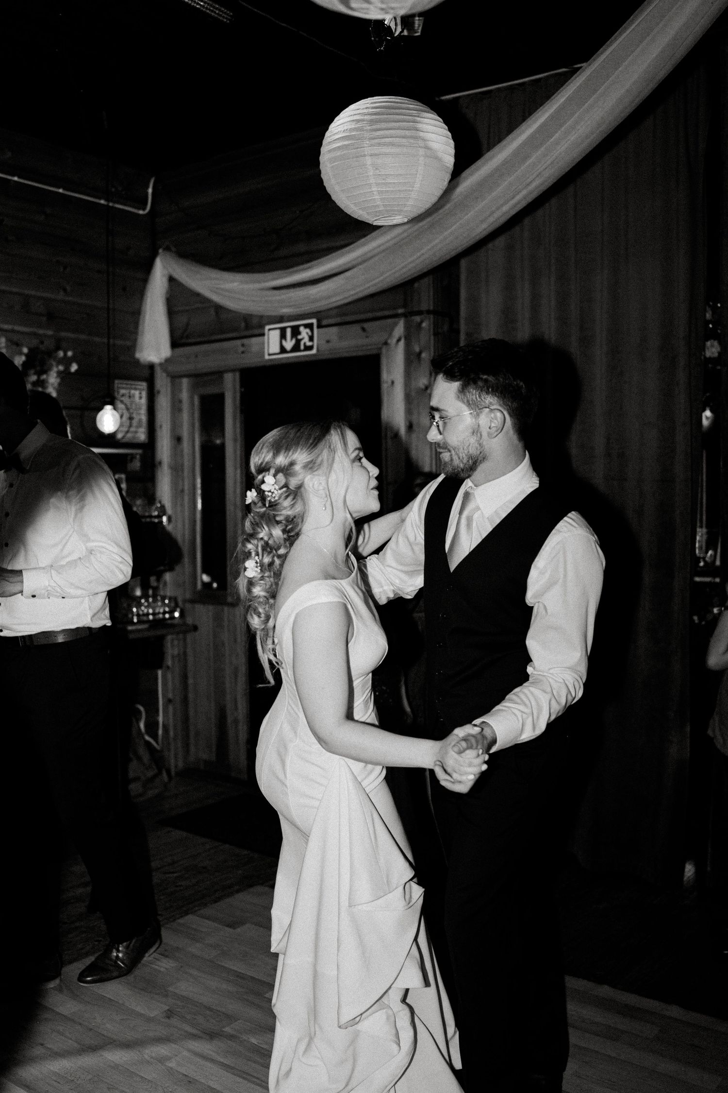A romantic dance moment under paper lanterns and draped fabric at an evening reception.