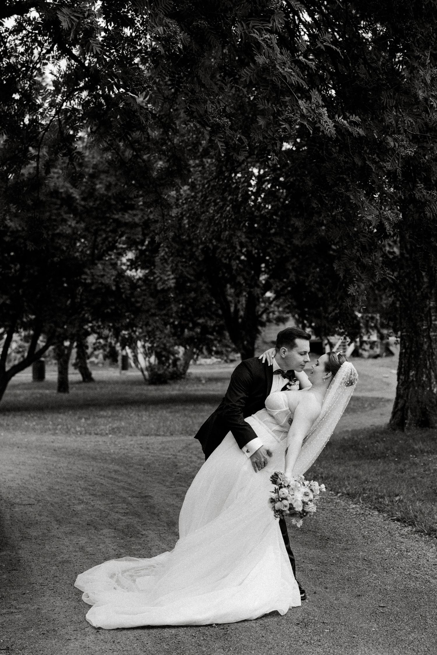 Black and white romantic wedding portraits under trees showing intimate moments.