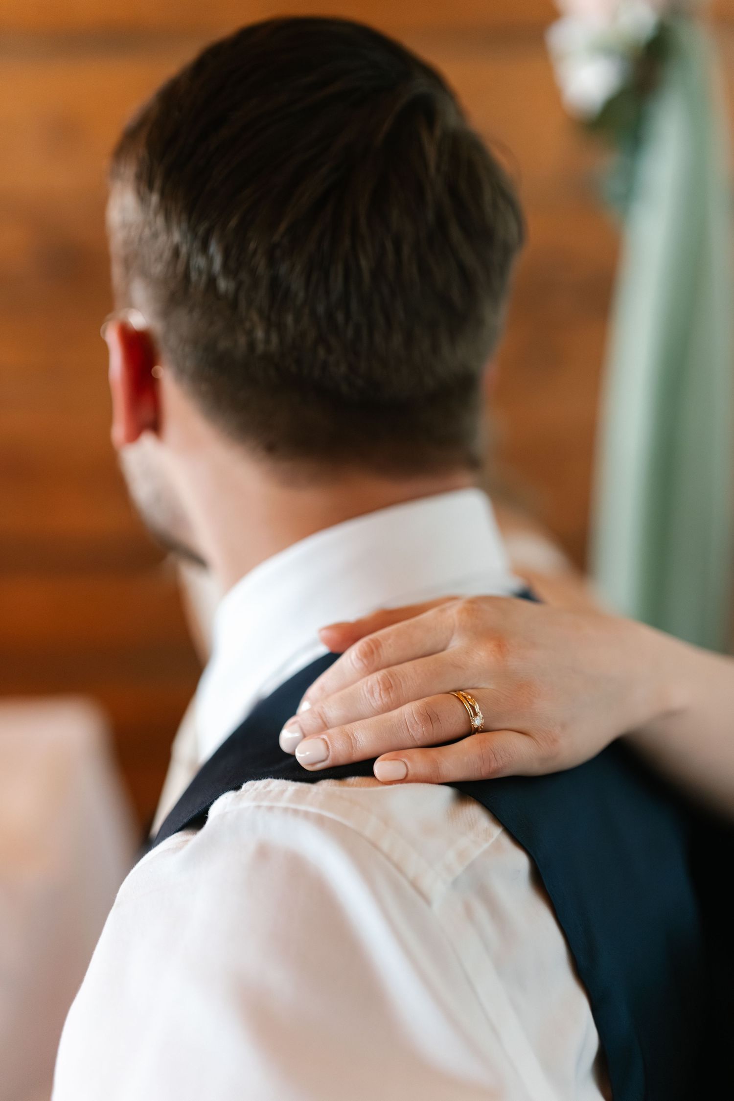 Close-up of hand with wedding ring resting on shoulder during intimate moment.