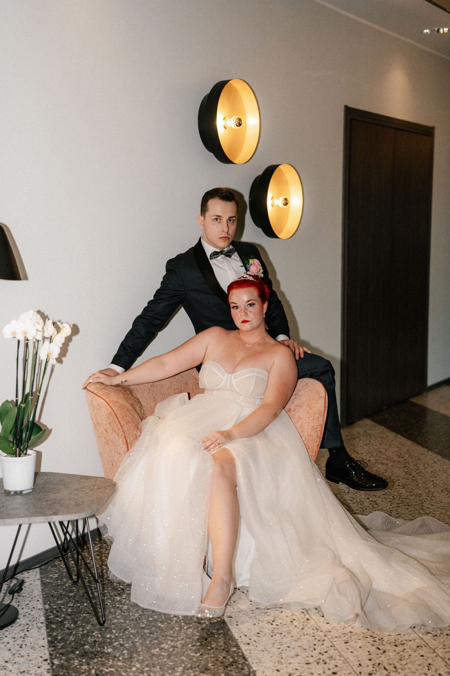Elegant wedding photos showing a couple posing on a plush sofa with dramatic lighting.