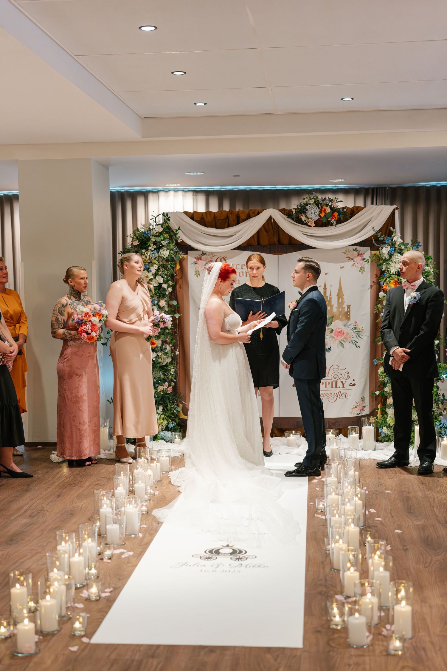 Wedding ceremony aisle lined with glowing candles leading to a floral arch.