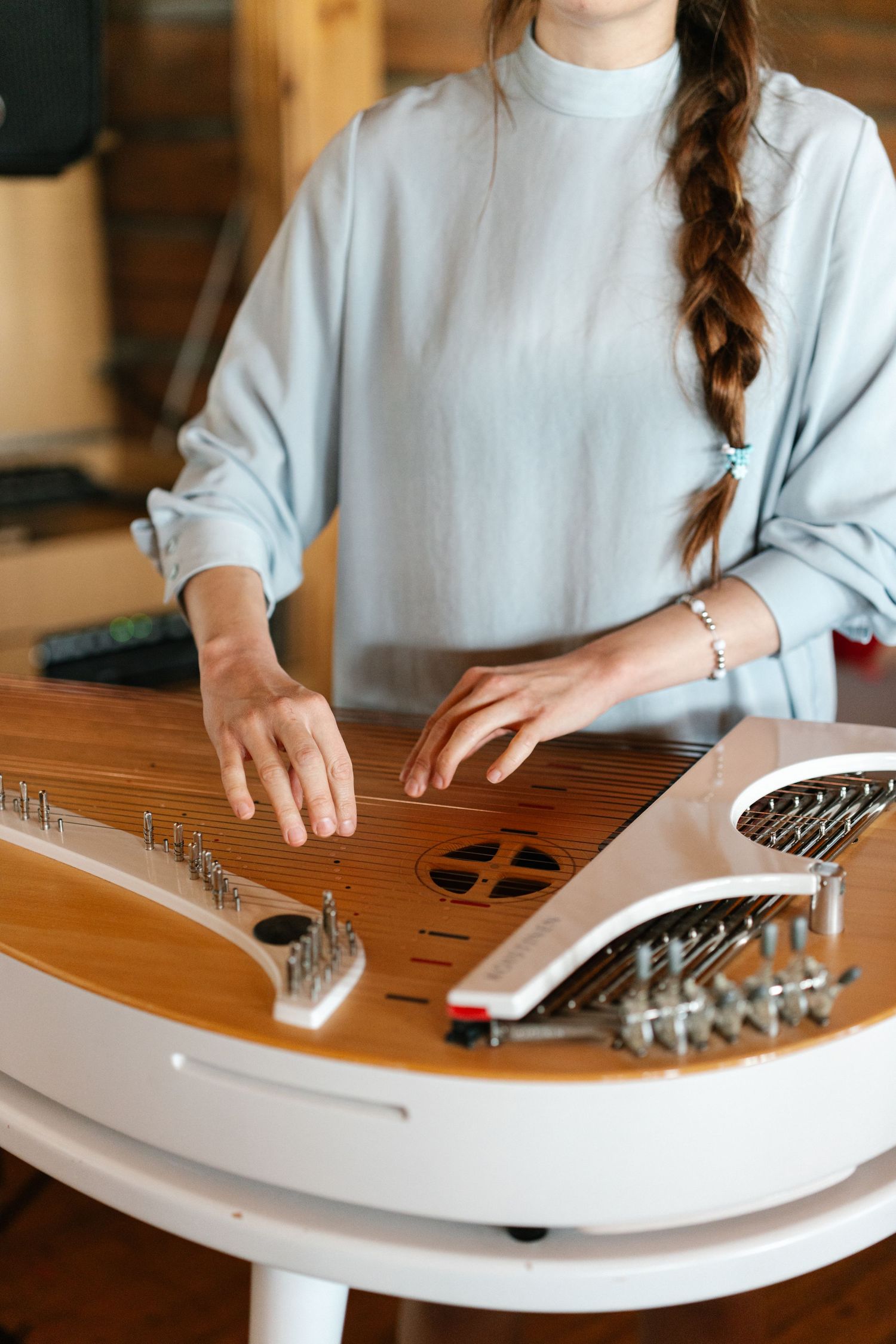 Musician playing a modern white electric harp instrument in casual attire.