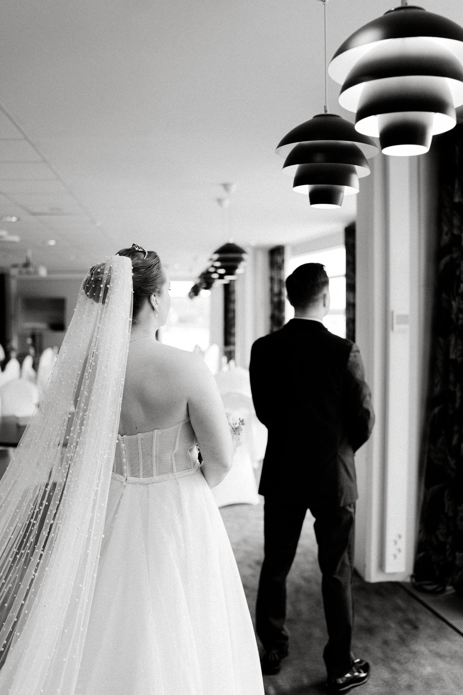 A series of black and white wedding photos showing a first look moment in a hallway.