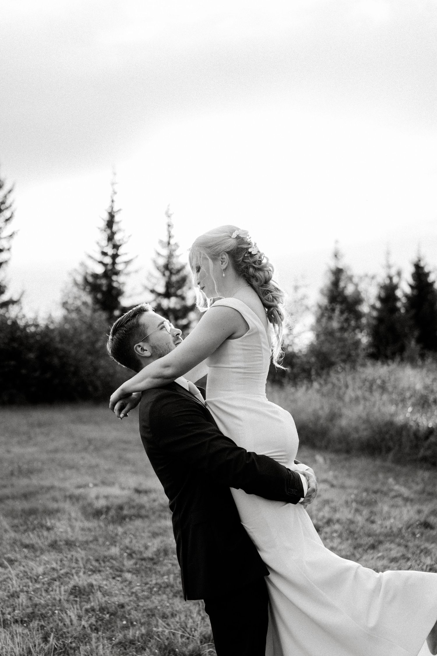 Black and white portrait of newlyweds in an intimate embrace outdoors.