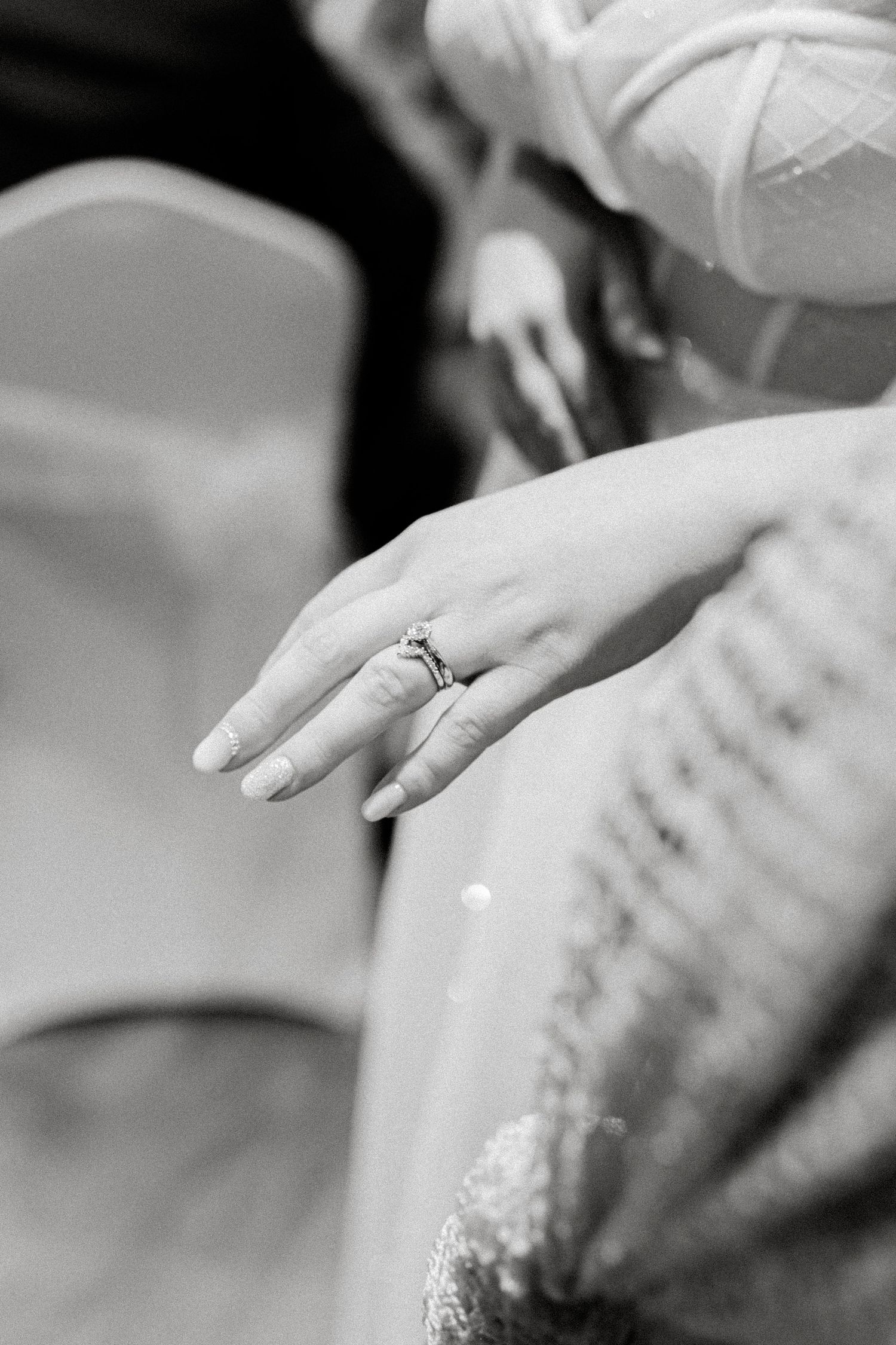 Black and white detail shot of hands and rings during a wedding ceremony.
