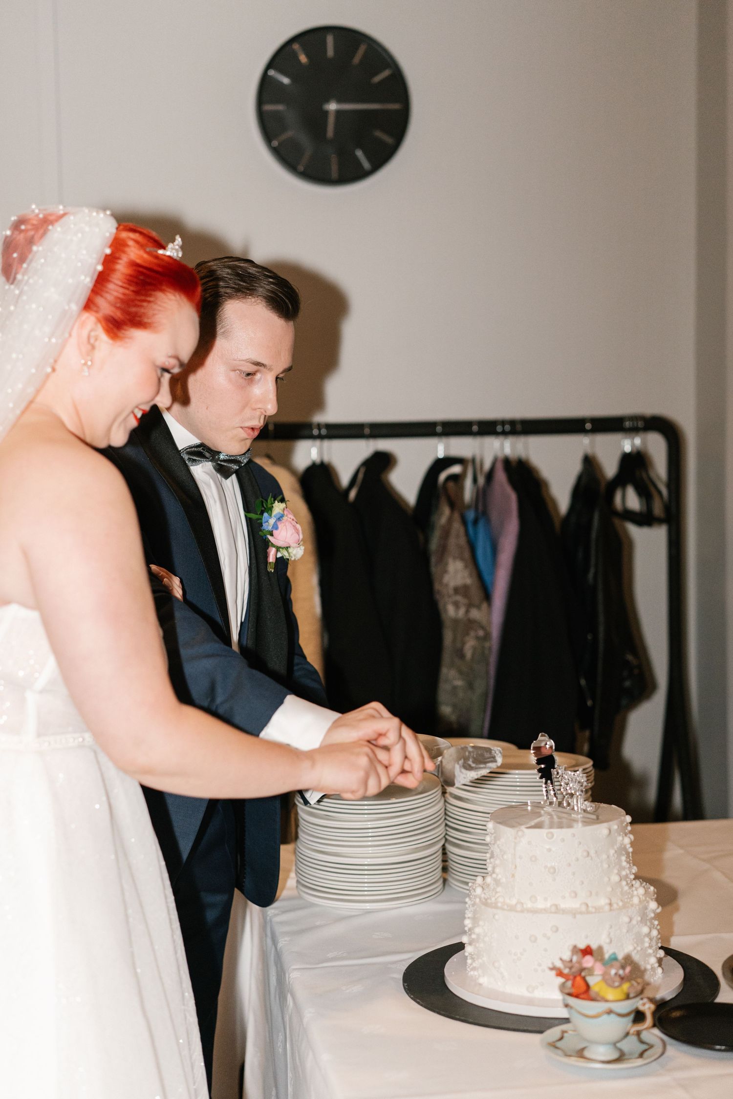 Couple cutting their white wedding cake at reception.