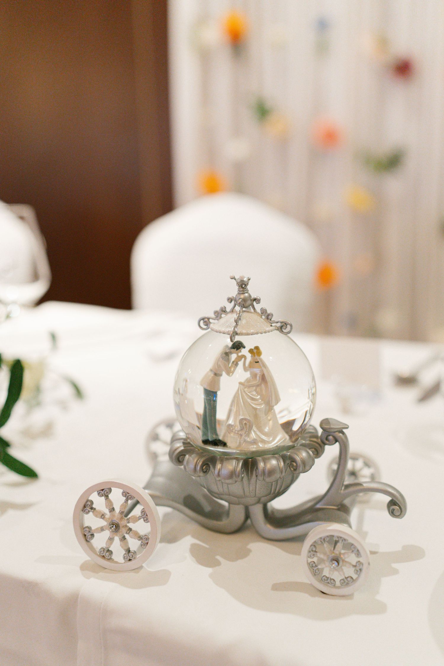 Delicate silver carriage decorations displayed on white tablecloths at a wedding reception.