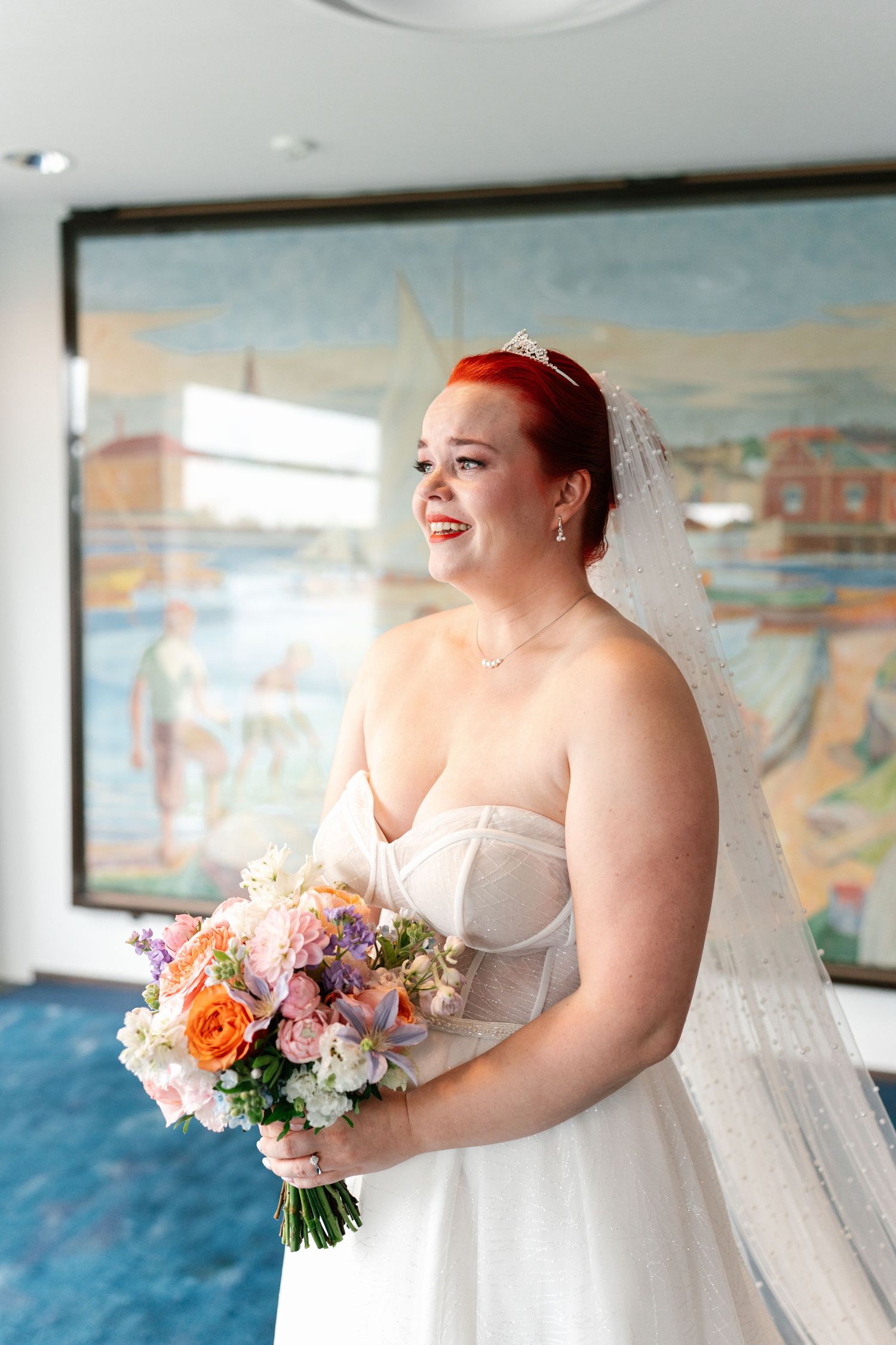 A joyful moment with colorful wedding bouquet against coastal-themed wall art.