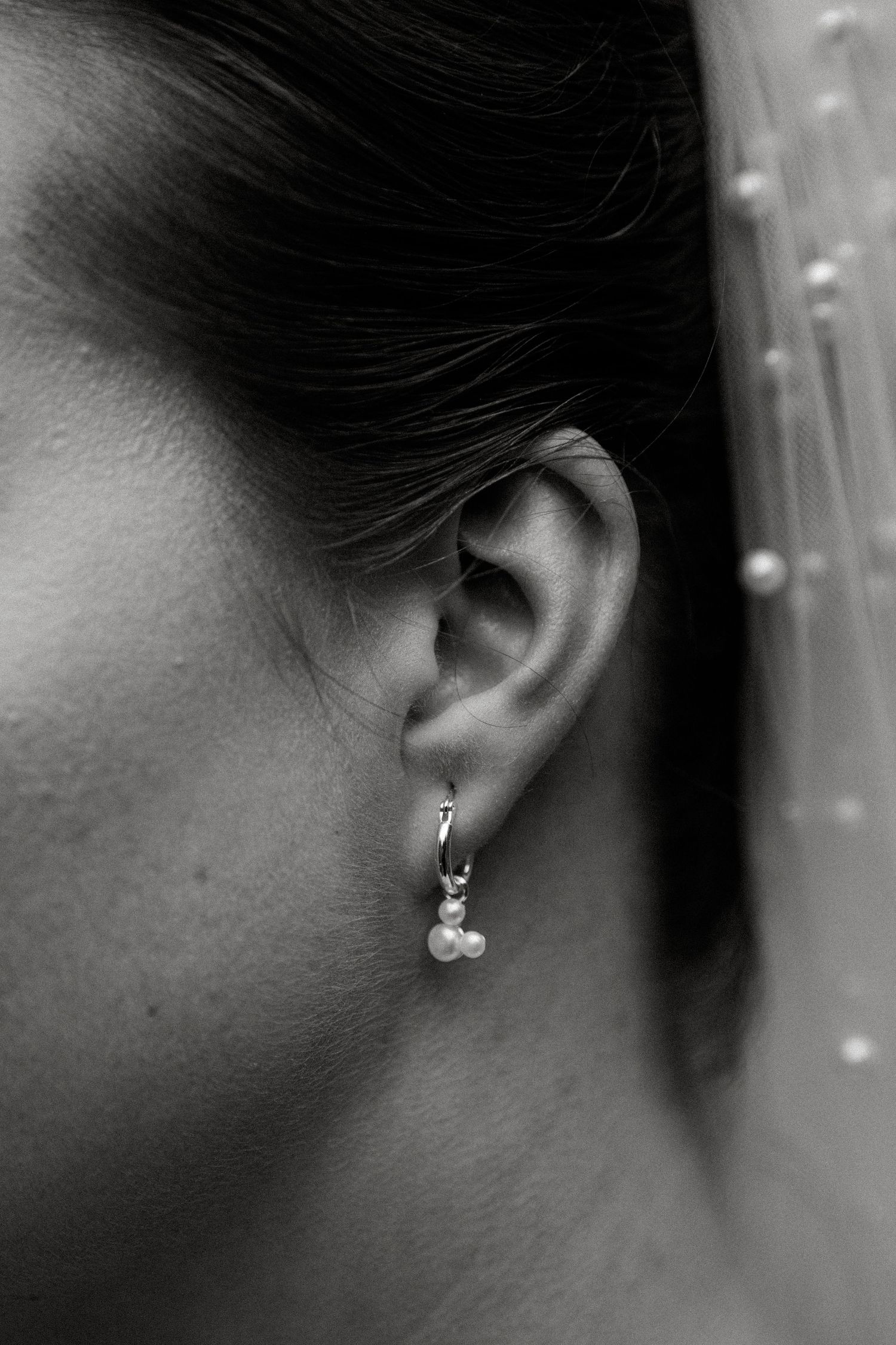 Close-up black and white detail shots of pearl earrings and bridal jewelry.