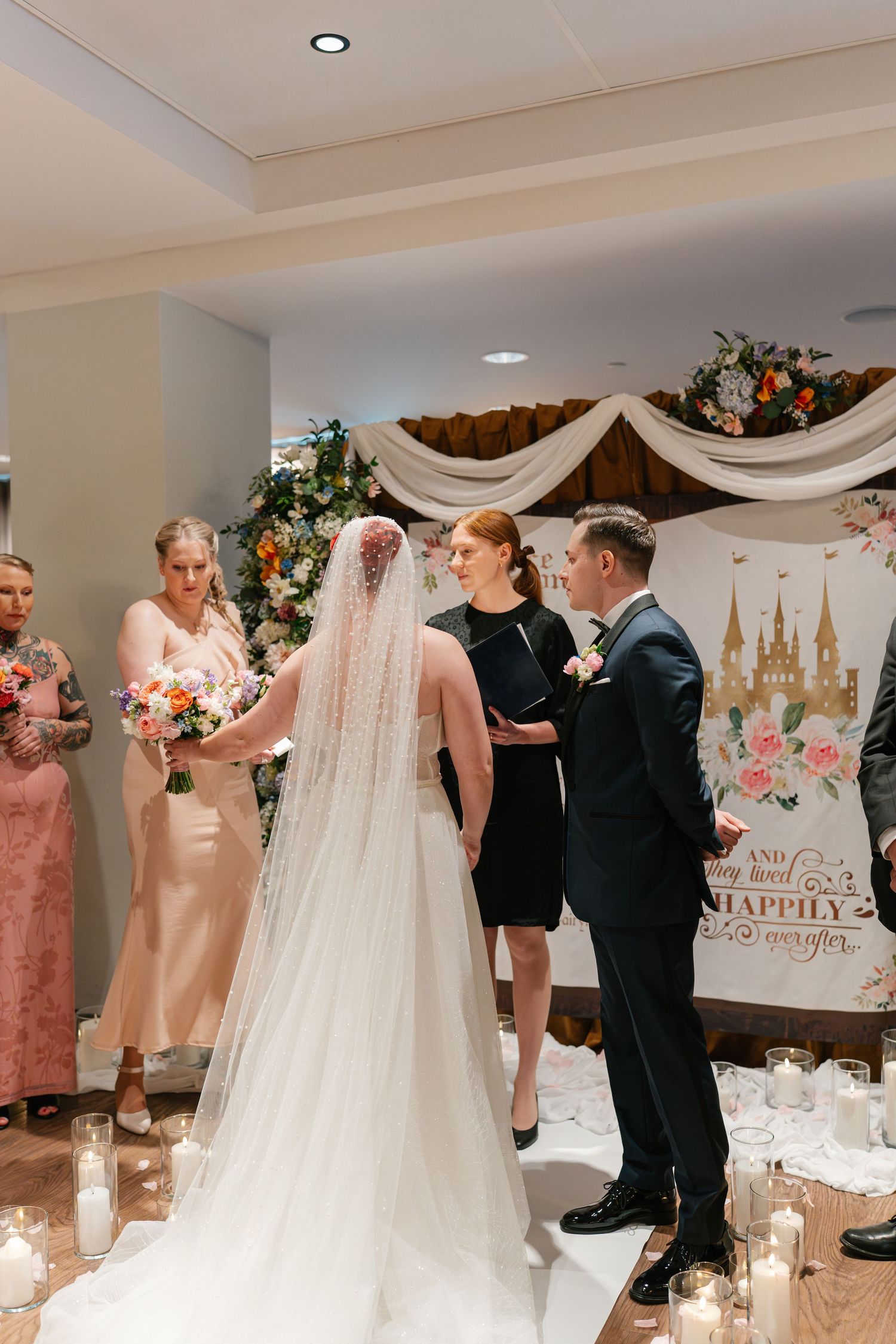 Wedding ceremony space decorated with white draping, floral arrangements and elegant seating.