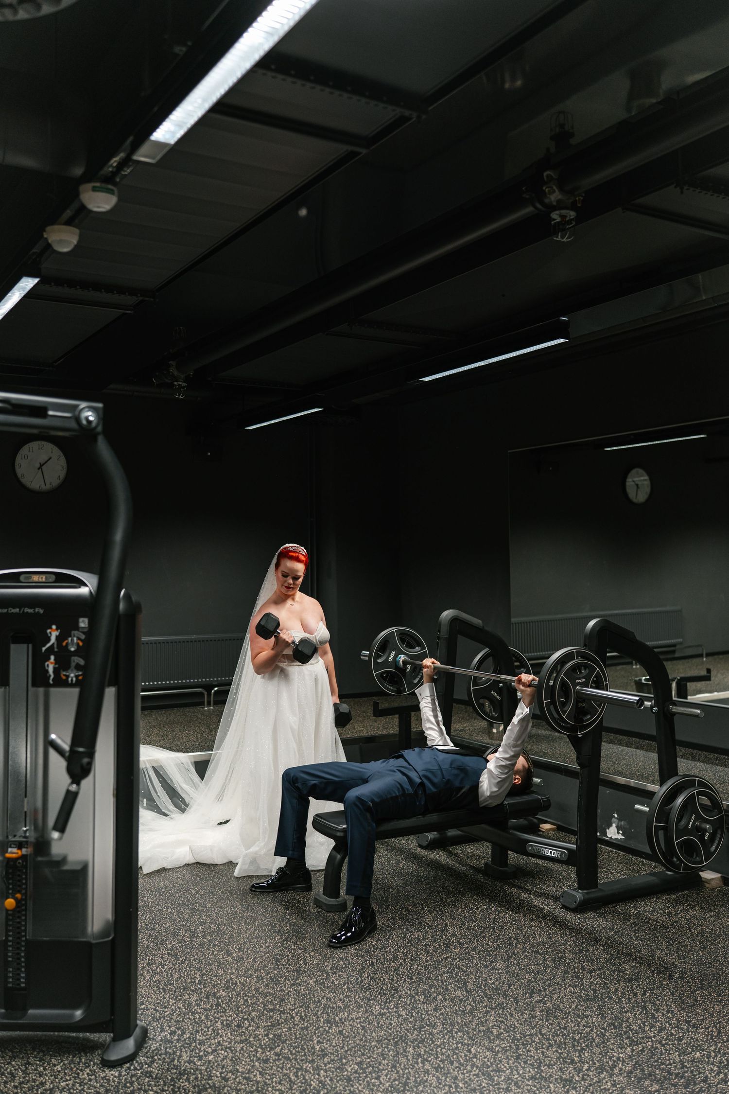 Creative wedding photos taken in a dark gym with exercise equipment.