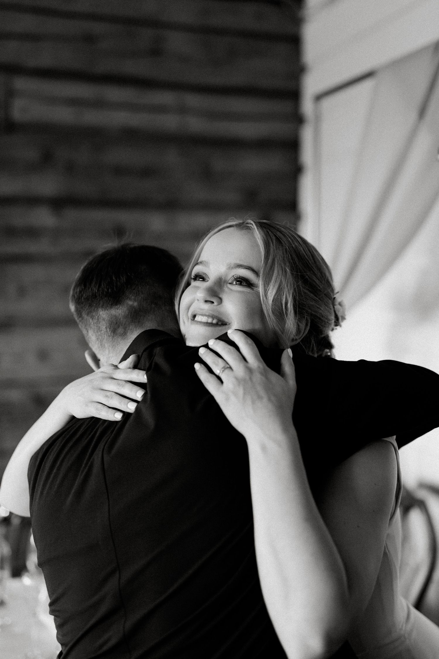 Emotional embrace captured in black and white at wedding celebration.