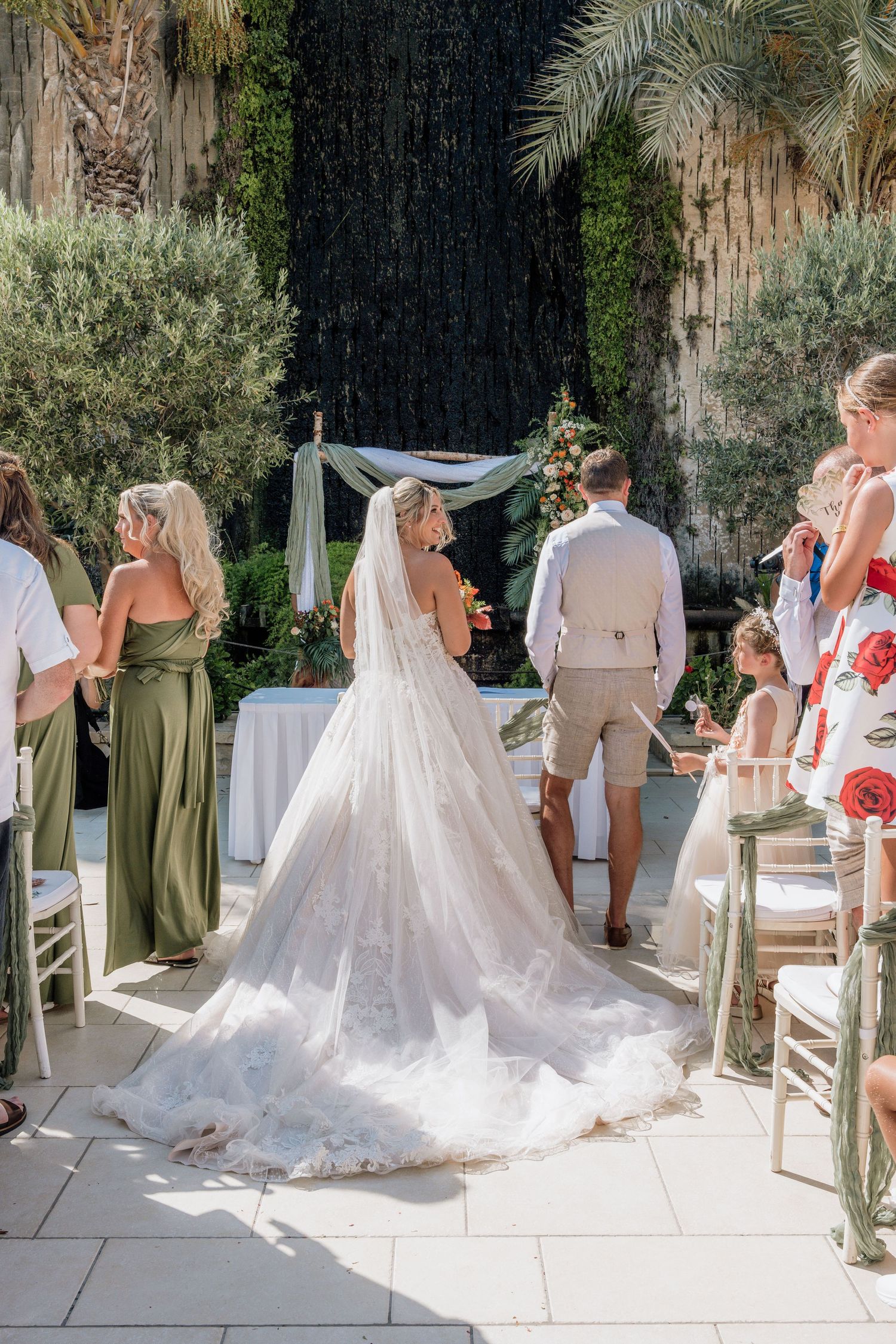 Outdoor wedding ceremony setup with flowing white drapery and palm trees, creating a romantic and elegant atmosphere.