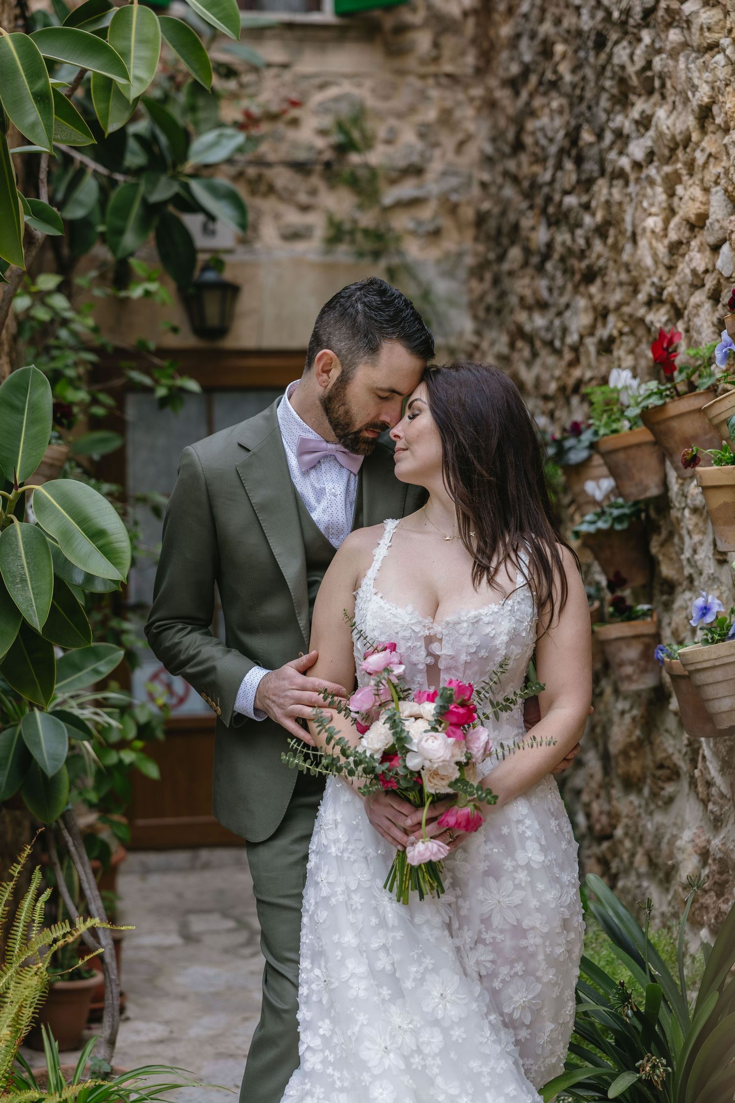 Newlyweds share an intimate moment in a charming Valldemossa garden, surrounded by stone walls and lush greenery in Mallorca.