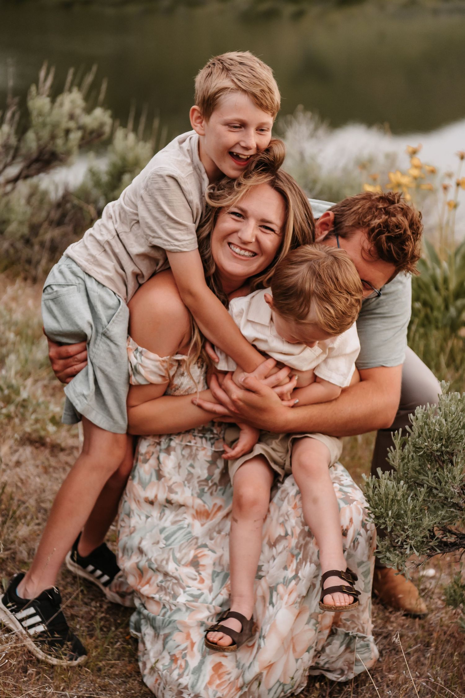 A playful family sharing laughs and embraces while sitting outdoors.
