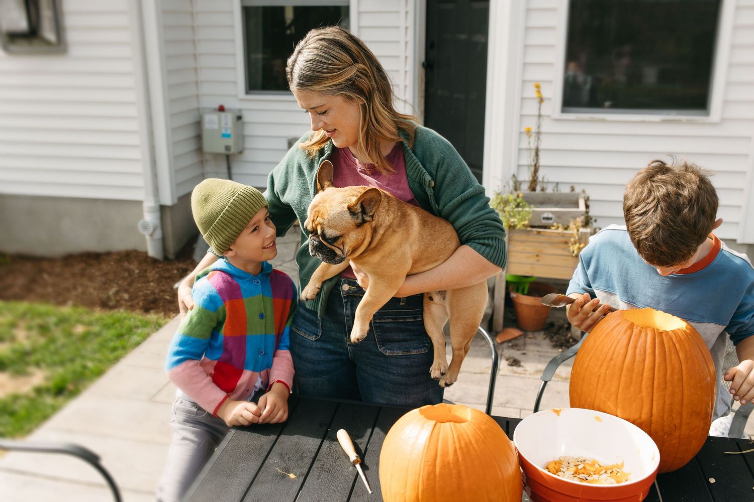 People carving pumpkins together on a porch during fall season activities.