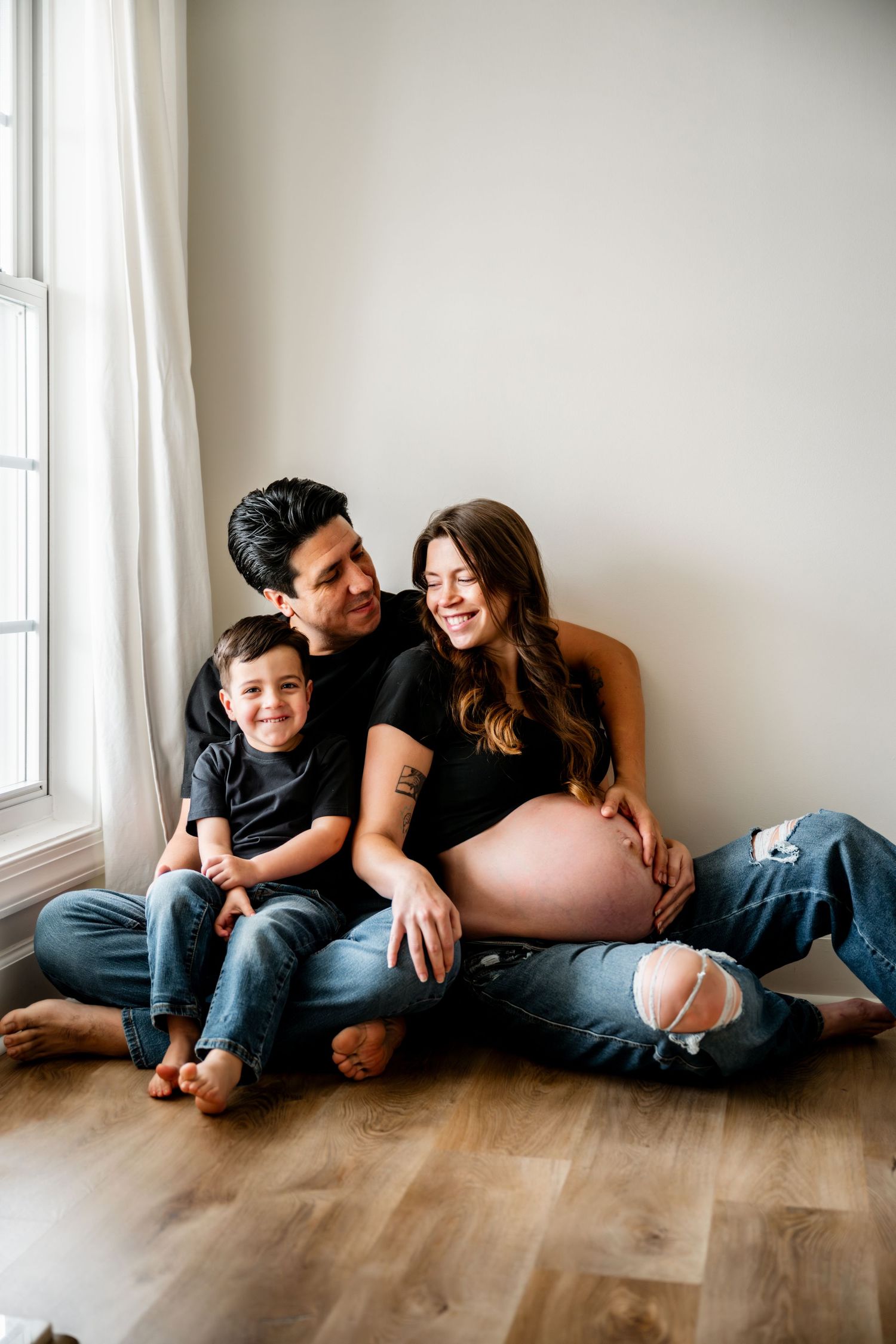 Candid family moments captured in a series of black and white photos showing playful interactions on a hardwood floor.
