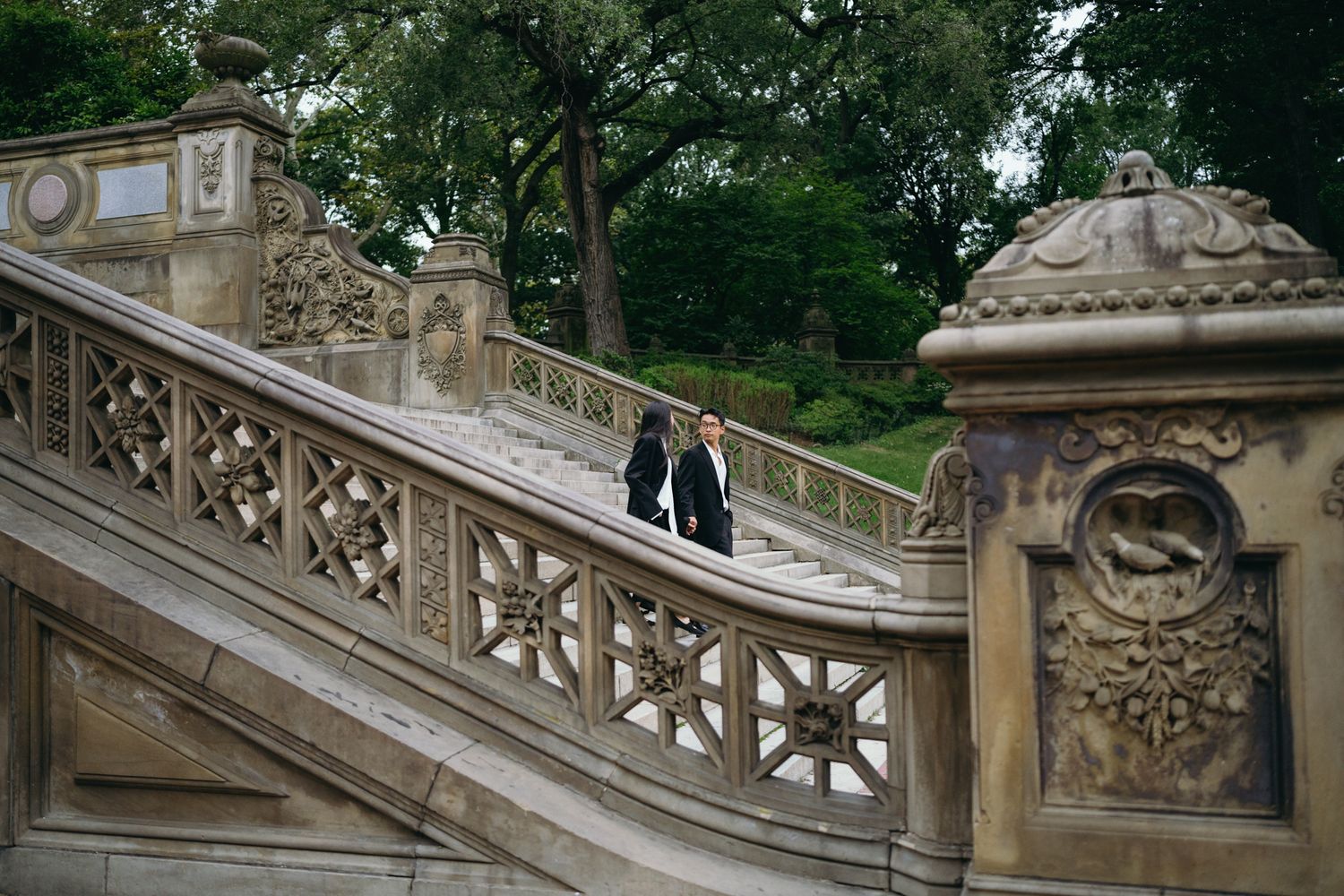 Two people walking on ornate stone staircase at Bethesda Terrace in Central Park, New York City.