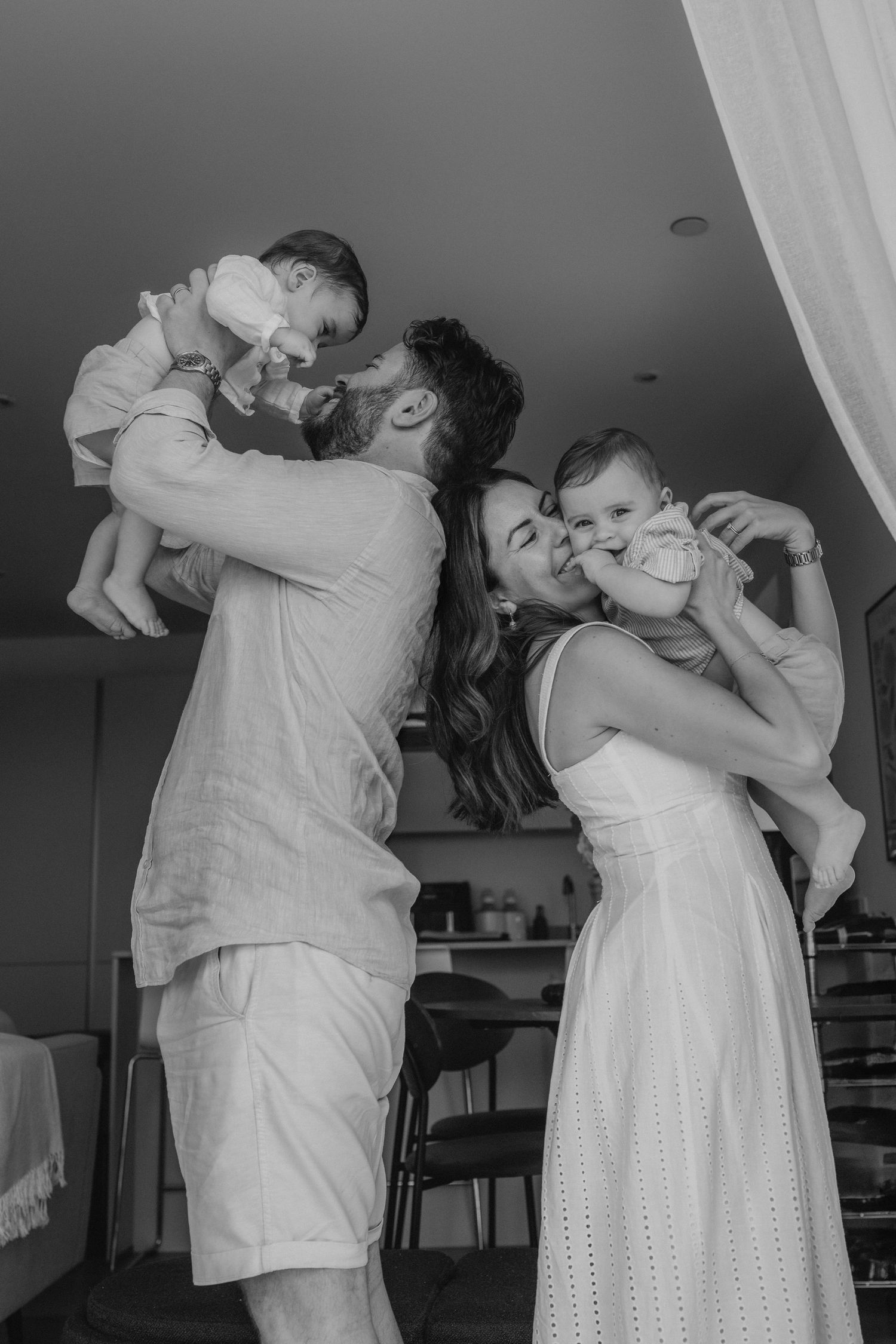 a mum an dad each holding a twin boy in their arms and looking at them lovingly