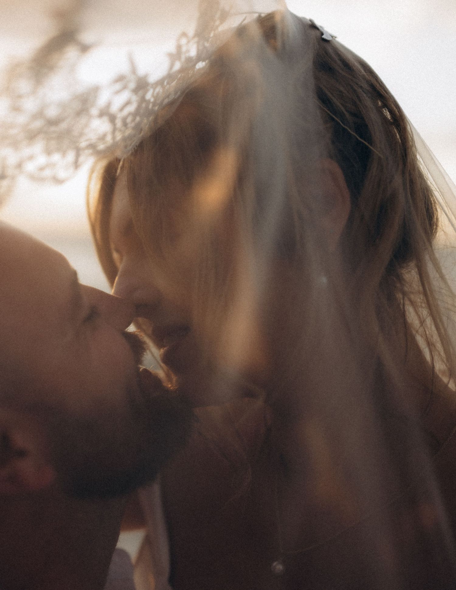 a couple almost kissing underneath a veil