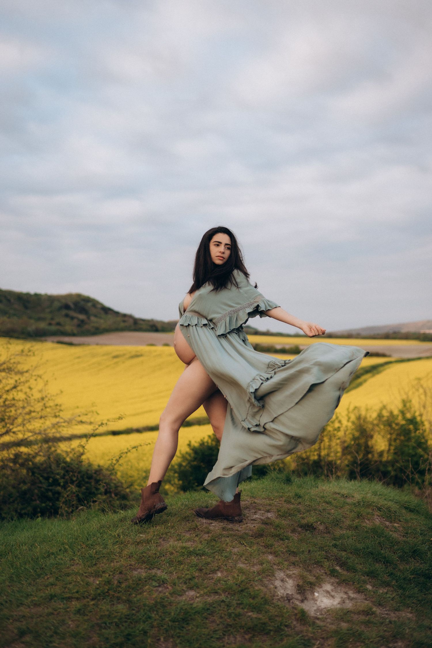 A pregnant woman posing near a rapeseed filed