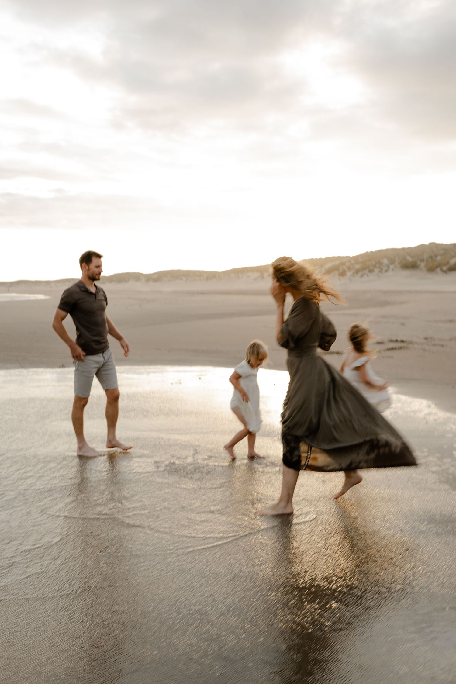 A candid photo of a family walking on a beach during their family photo session in Kent