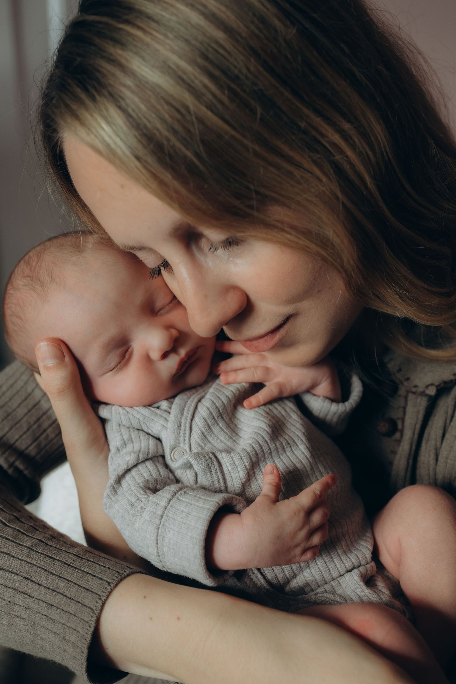 a mother holding her new born close to her face during a new born photo session in Richmond, London