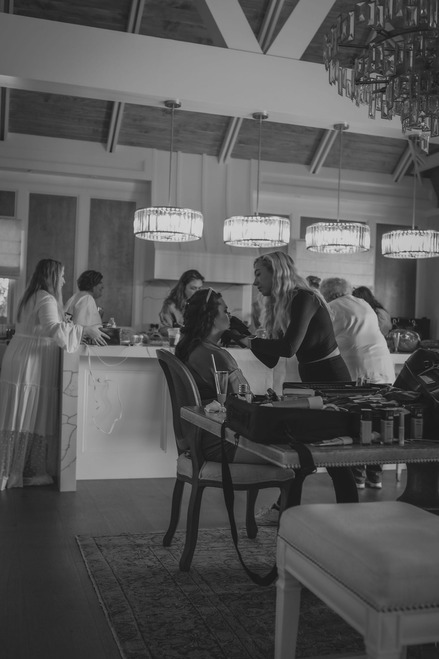 Restaurant guests dining under elegant crystal pendant lights in an upscale dining room with a black and white aesthetic.
