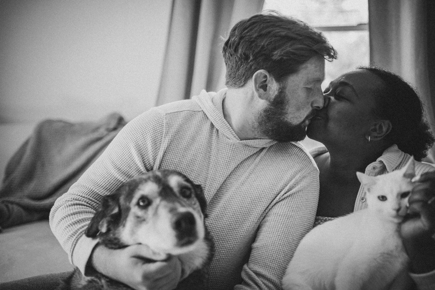 A couple shares tender moments with their small white dog in a series of black and white photographs.