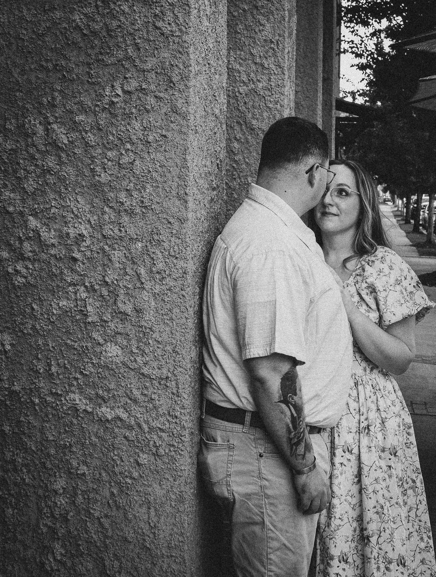 A romantic black and white moment between a couple against a textured wall.