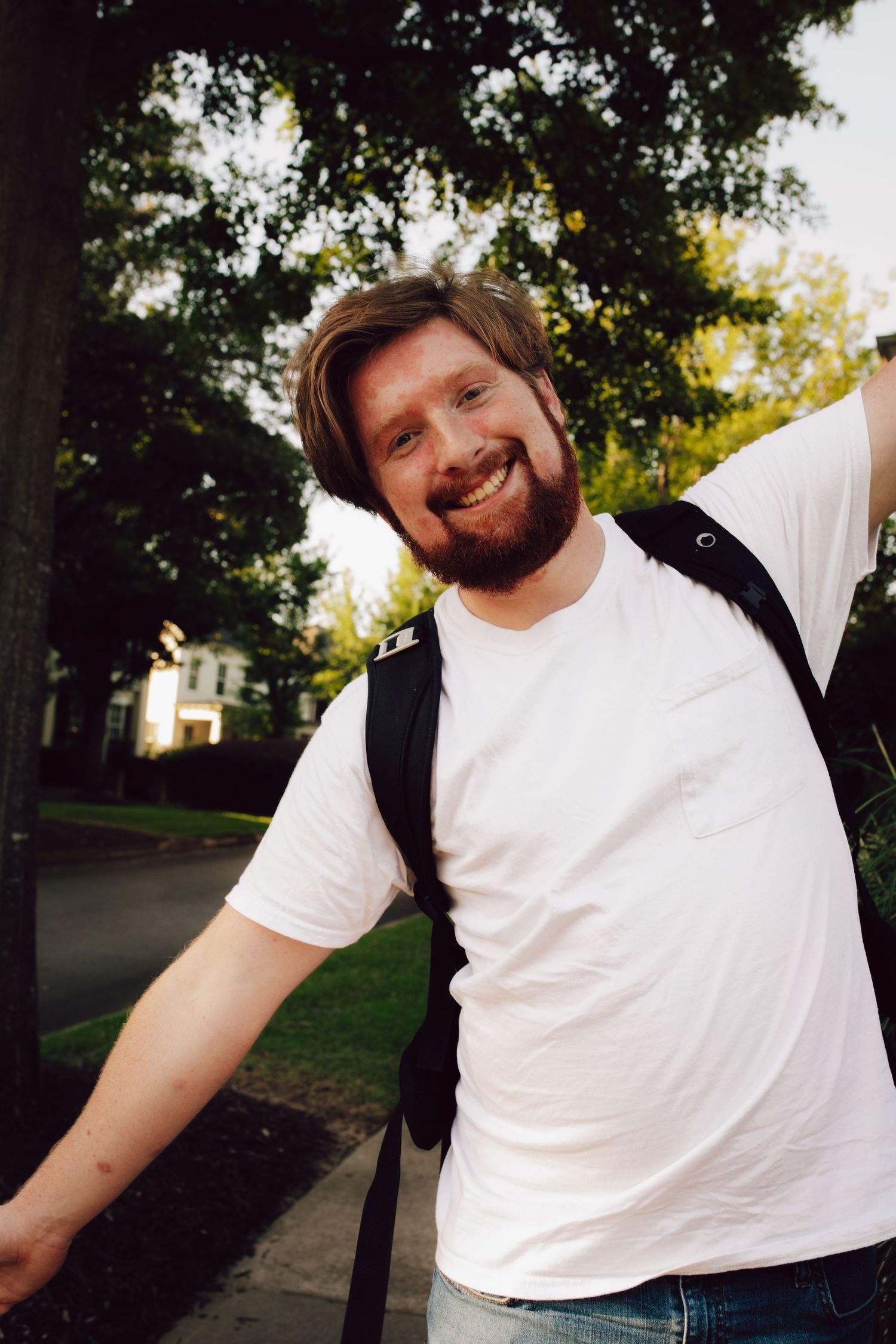 Casual outdoor portrait with natural backlight and trees.