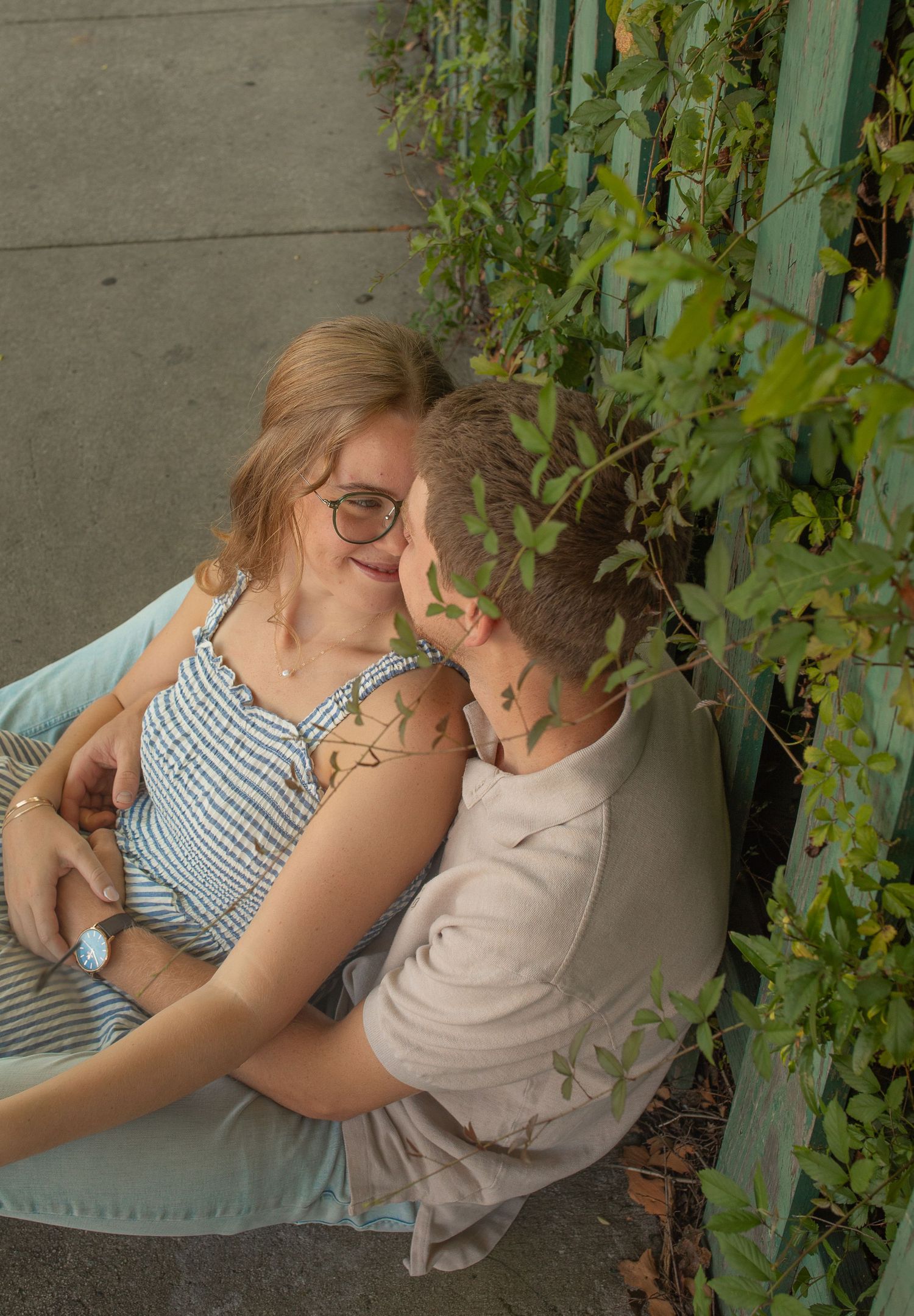 A tender moment shared between two people in a garden setting with climbing vines and greenery in the background.